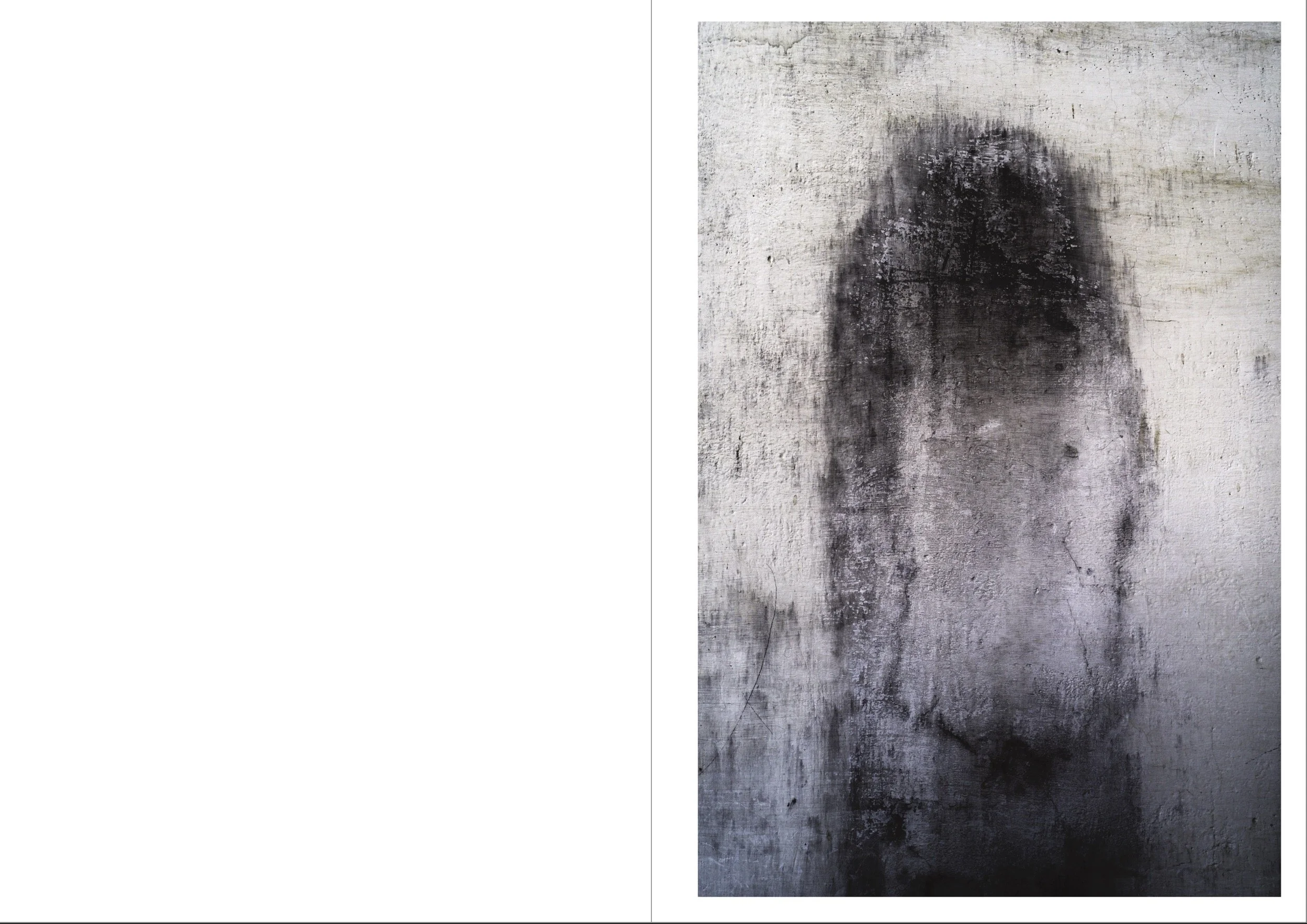 Graffiti of a person's face painted in black on a weathered, white concrete wall.