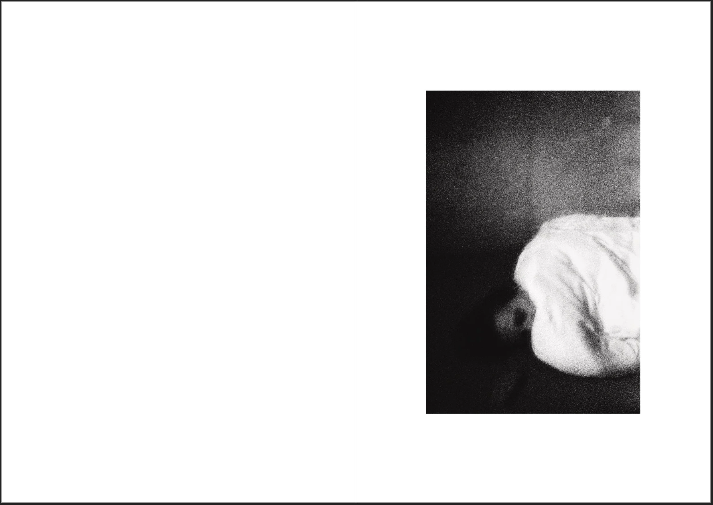 A black and white photo showing a person lying on a bed with their face turned away, covered by a white sheet, in a dark room.