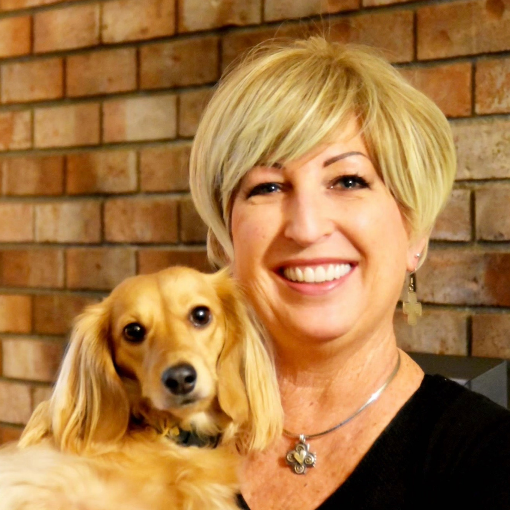 Joy holding her dachshund Bunny, smiling together in a warm, friendly portrait, personal behind the brand moment for Scatter Joyfulness Greetings