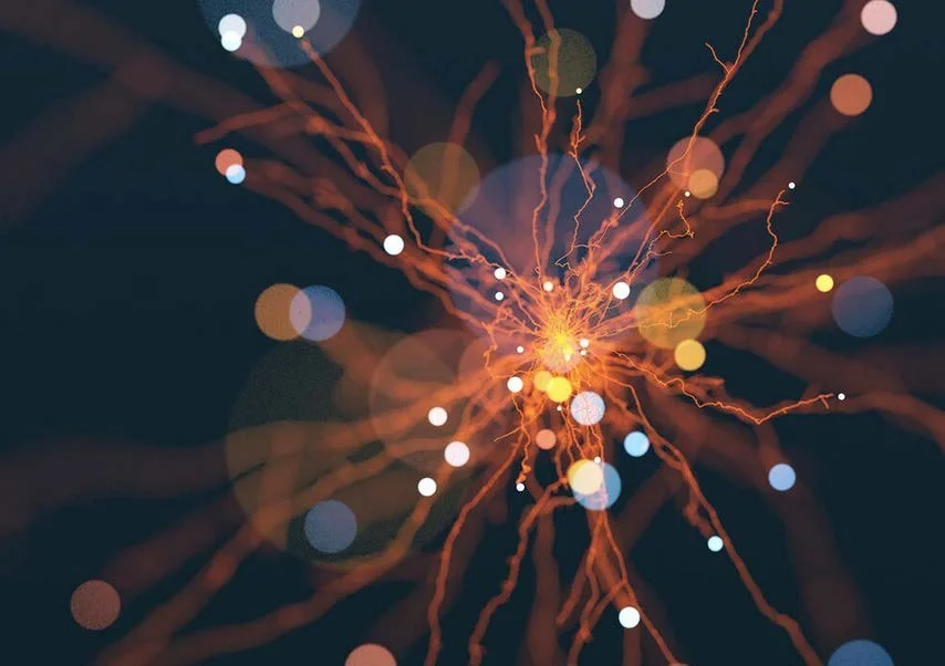 A close-up view of a sparkler producing bright orange and yellow sparks with bokeh effects in the background.