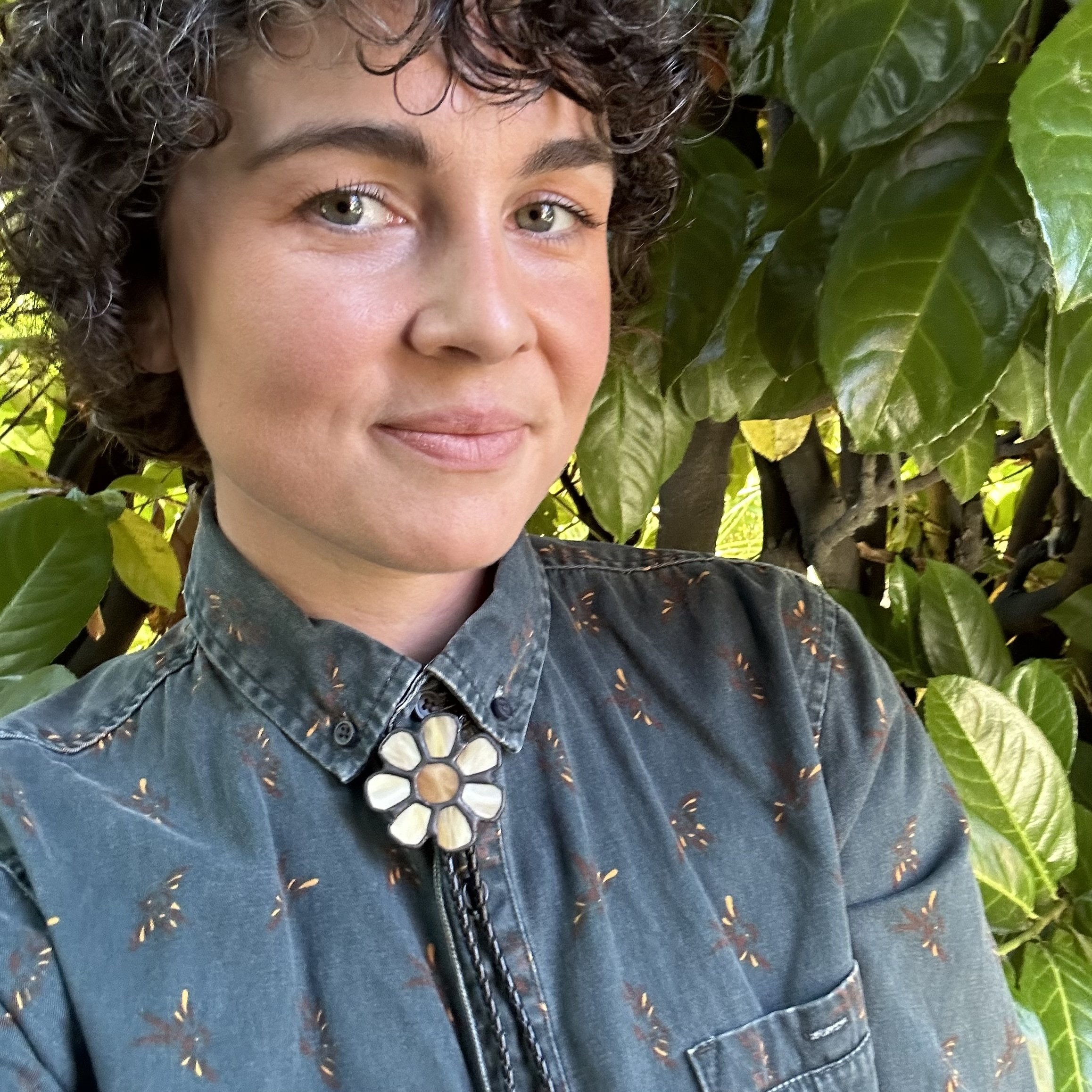 Image of a young woman with curly hair wearing a stained glass bolo tie