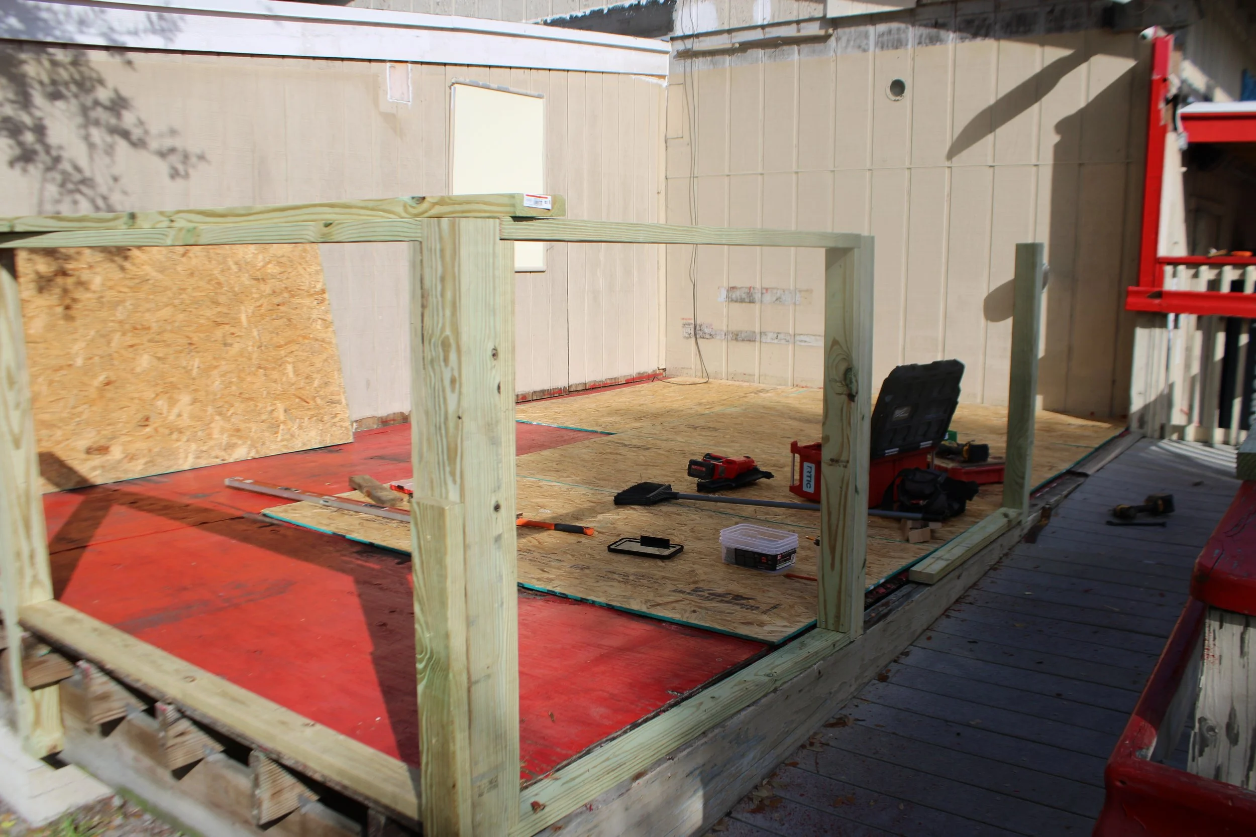 Under construction wooden deck with tools and supplies on a partially built frame.