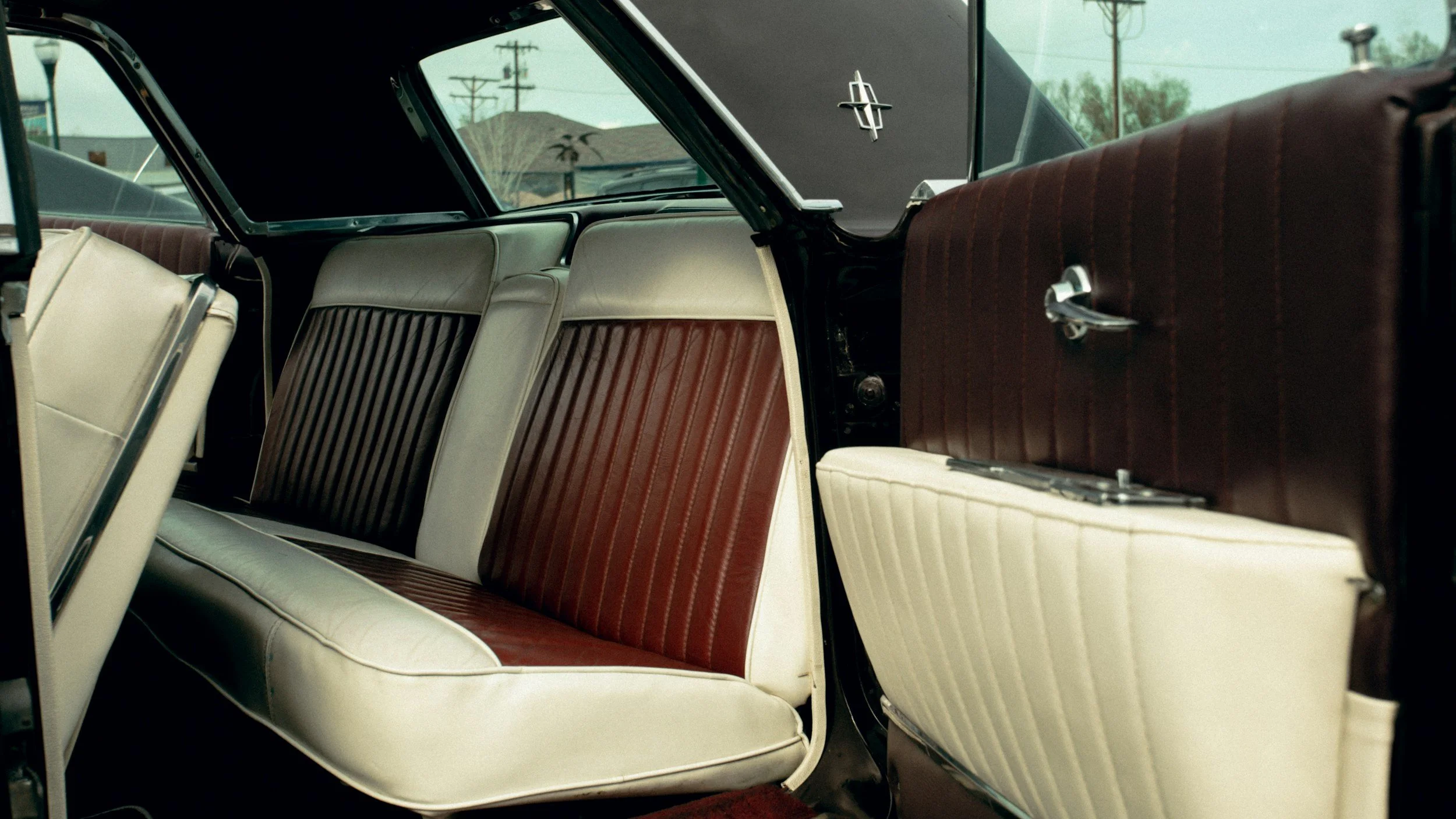 Interno di un'auto d'epoca con sedili in plastica bianca e marrone e pannelli delle porte abbinati.