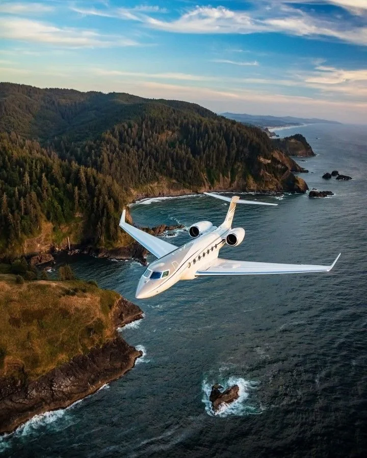 Aereo privato che sorvola una costa rocciosa e verdeggiante con mare circondante, sotto un cielo con nuvole leggere.