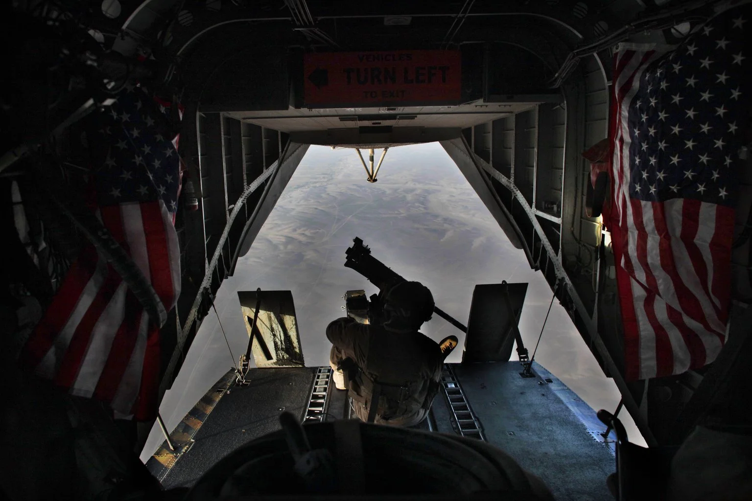 On the back bay of Helo, a gunner looks over the terrain of central Helmand Province, the last Taliban stronghold in central Helmand Province.