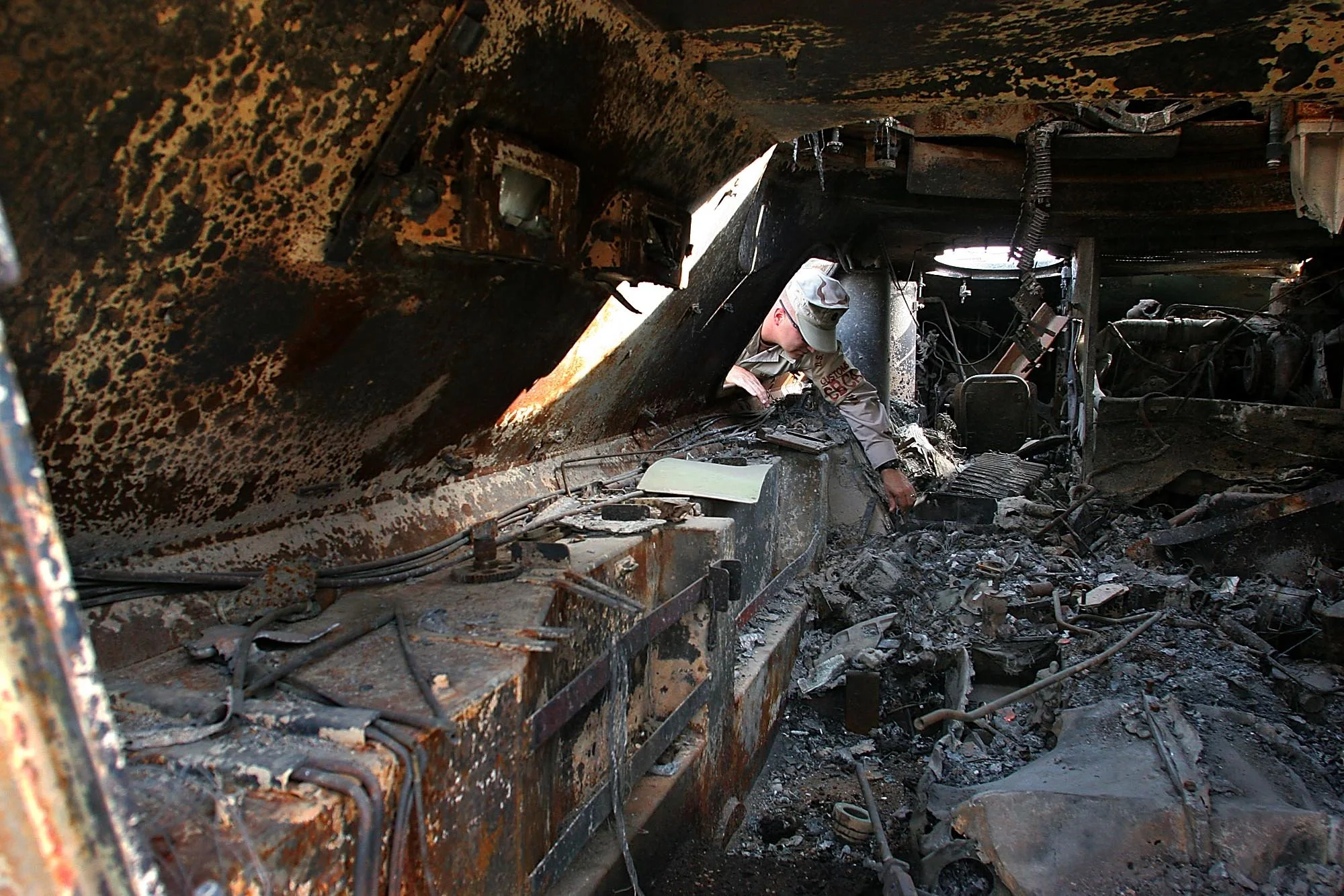 U.S. Navy Customs Supervisor Chief Donald Hatch inspects the interior of a light armored vehicle struck by an RPG in Iraq, now at the supply yard of Camp Arifjan, Kuwait, on December 7, 2005. The blast’s extreme heat melted the interior and blistered
