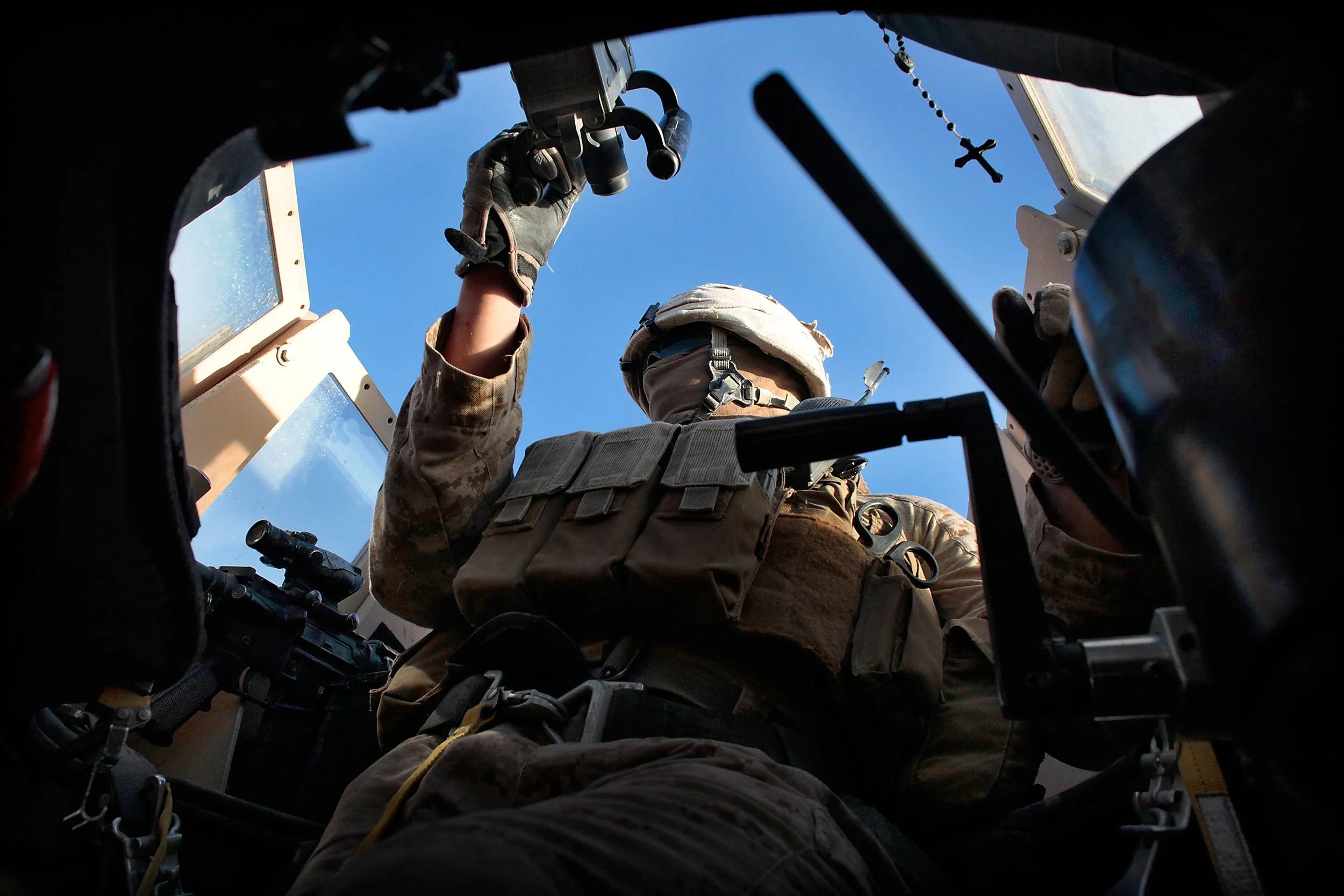 A U.S. Marine stands guard during a patrol through the city. In Afghanistan — a nexus of insurgency and roadside threats — even routine driving carries life-threatening risk.