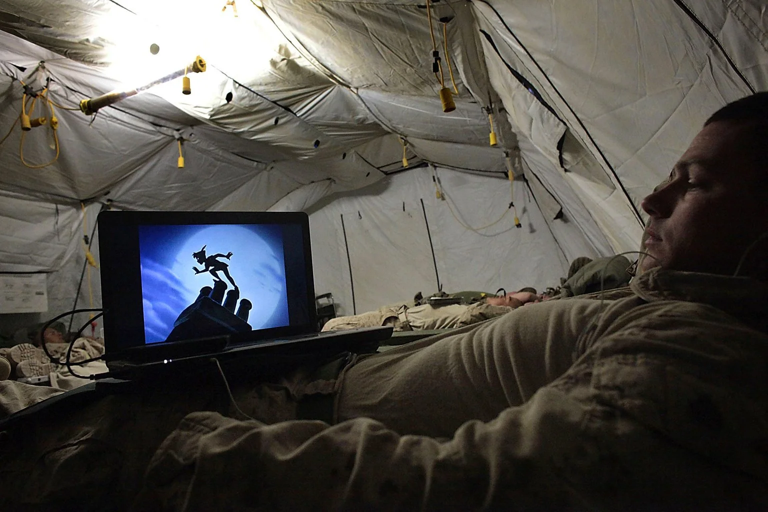 After returning from battle, a Marine unwinds by watching a Disney film on his laptop. At Camp Hansen — where amenities are scarce and entertainment is limited — animated movies offer a brief escape from the monotony and mental strain of war.