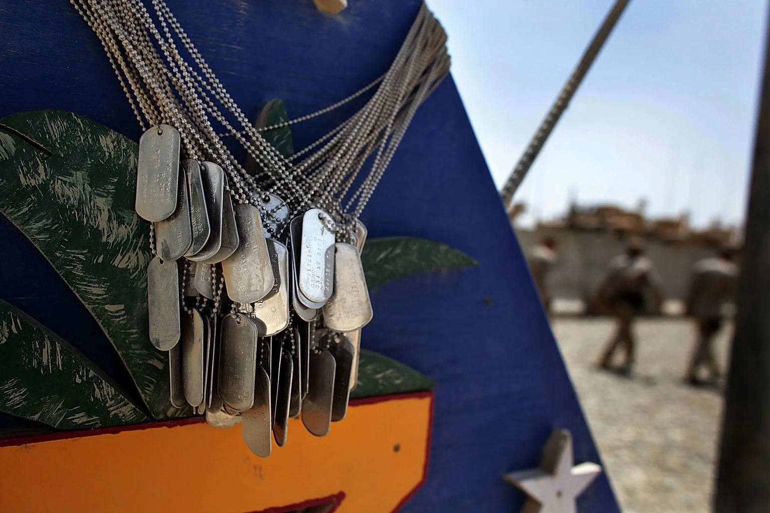 Dog tags of fallen Marines form a solemn memorial on a weathered signpost at Camp Dwyer in southern Afghanistan. Collected since October 2009, each tag honors a life lost — a quiet, enduring reminder of sacrifice.
