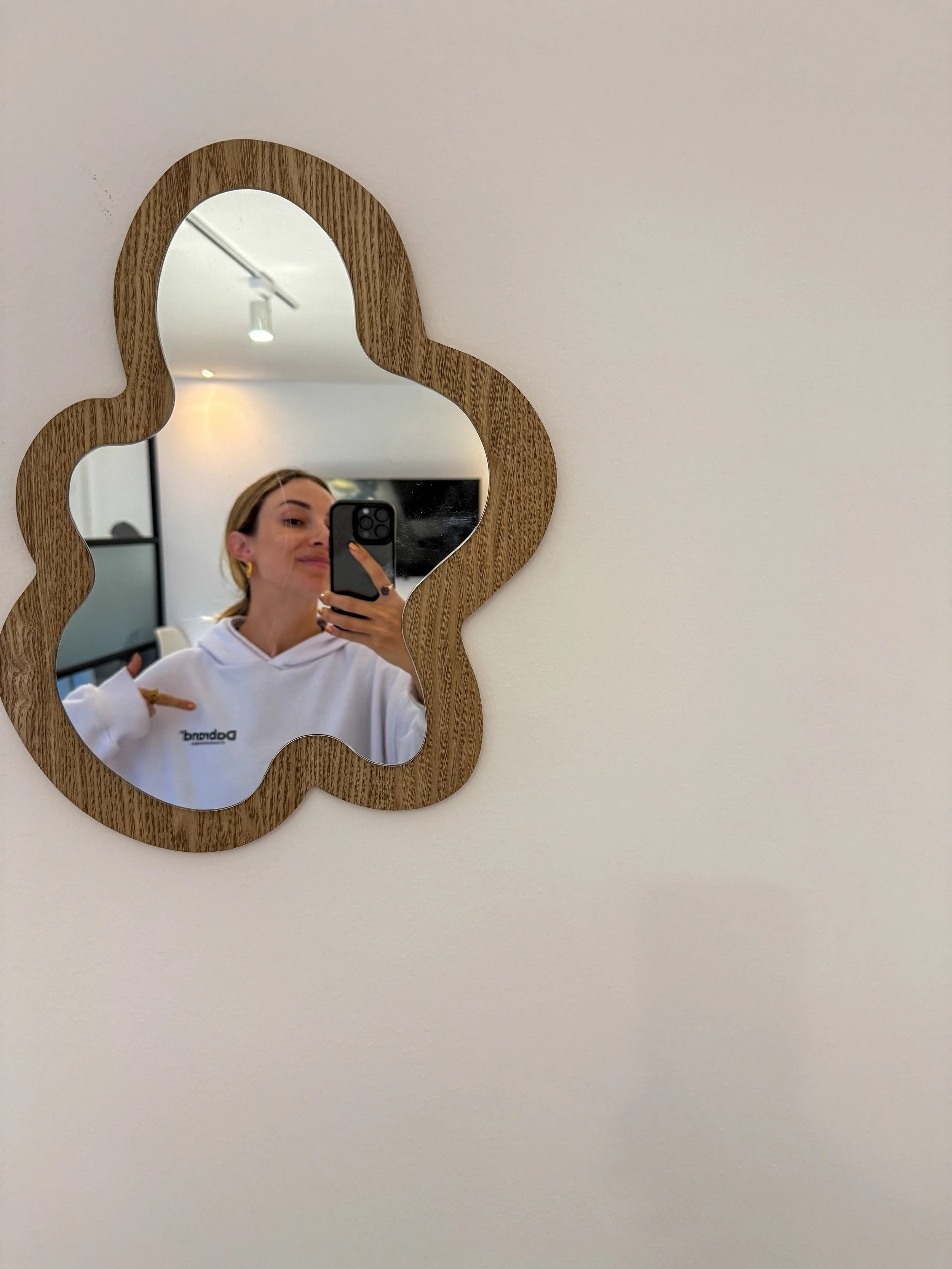 Mujer tomando selfie en un espejo de madera con forma abstracta