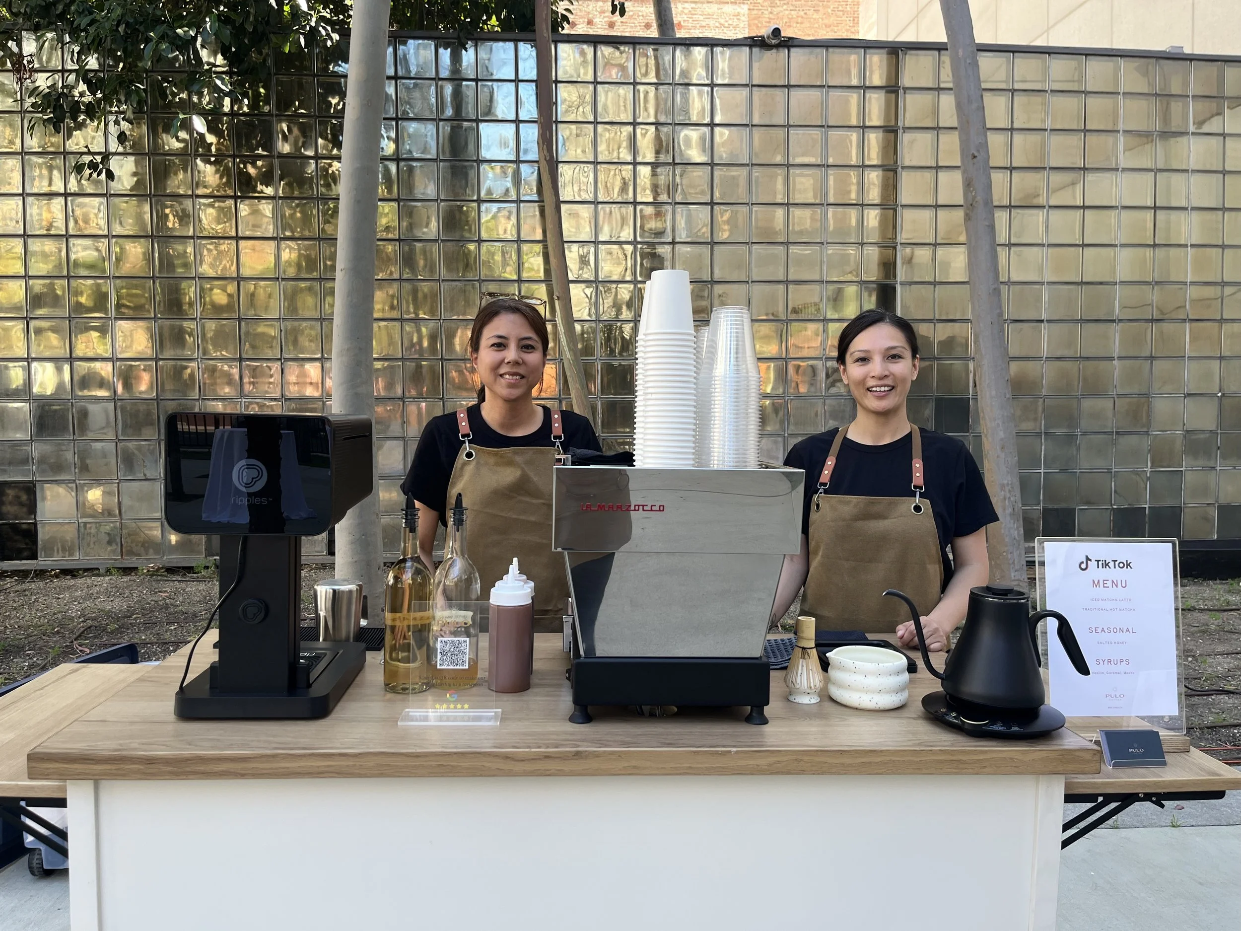 Pulo Coffee baristas at a matcha bar setup with La Marzocco espresso machine, ceremonial matcha tools, and branded menu at a brand activation event in Los Angeles