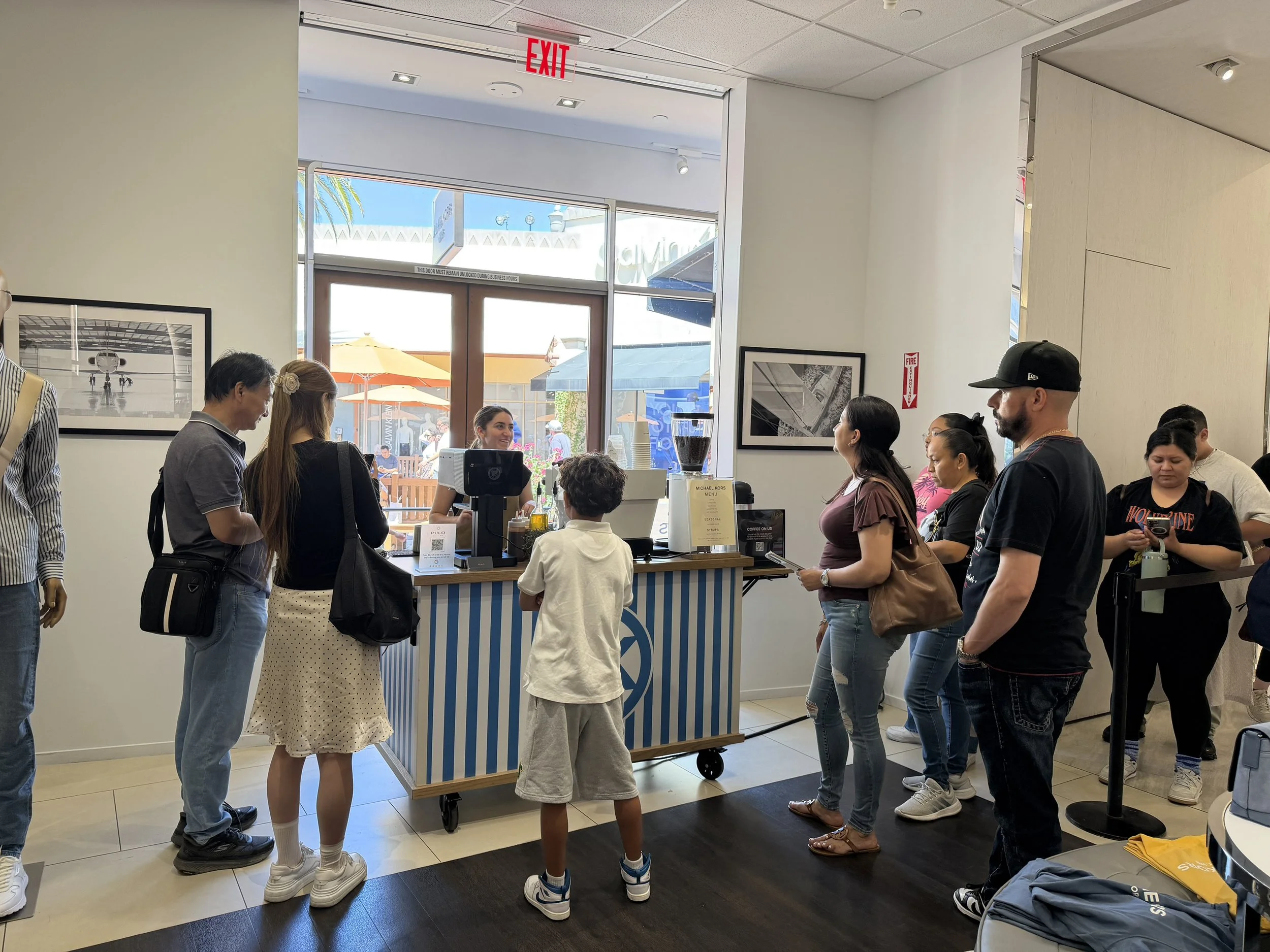 Guests lining up at a Michael Kors branded coffee cart by Pulo Coffee at a retail brand activation in Los Angeles