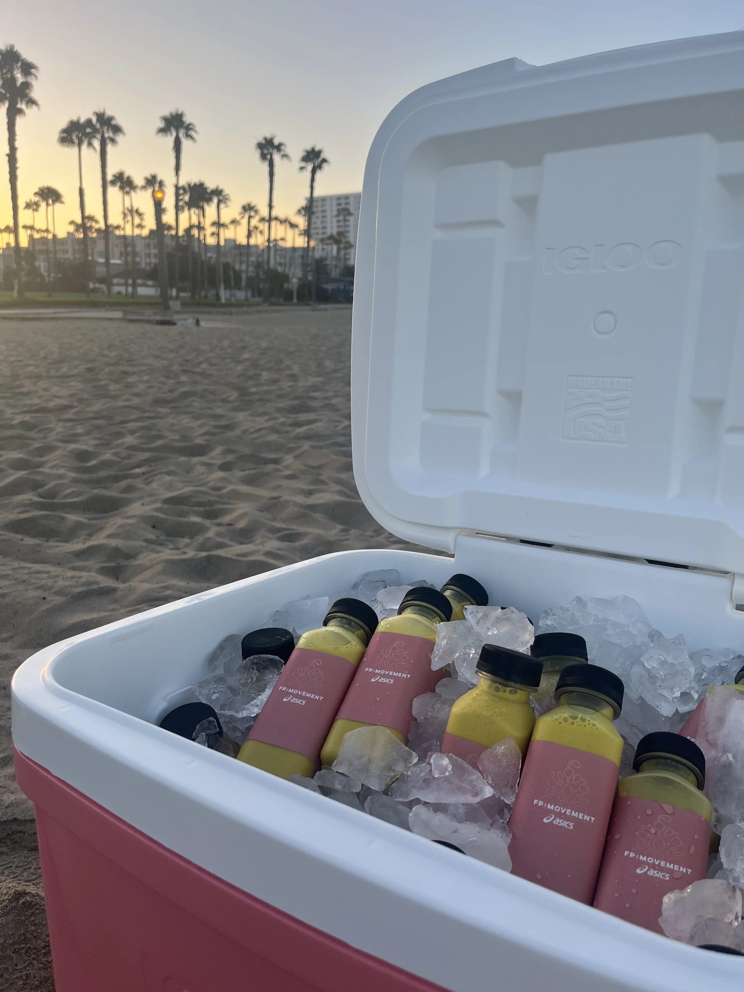 Pulo Coffee custom branded FP Movement x Asics bottled lattes in cooler at Santa Monica Beach outdoor brand activation at sunset Los Angeles
