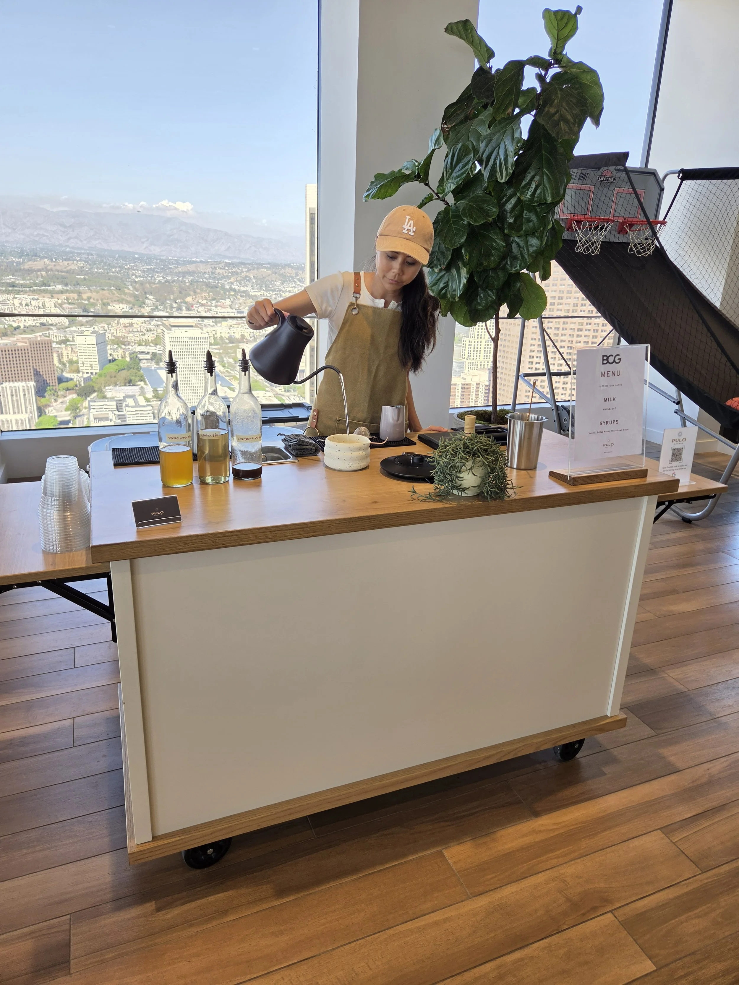 Pulo Coffee barista preparing matcha at mobile coffee cart with Los Angeles skyline view at BCG corporate office event