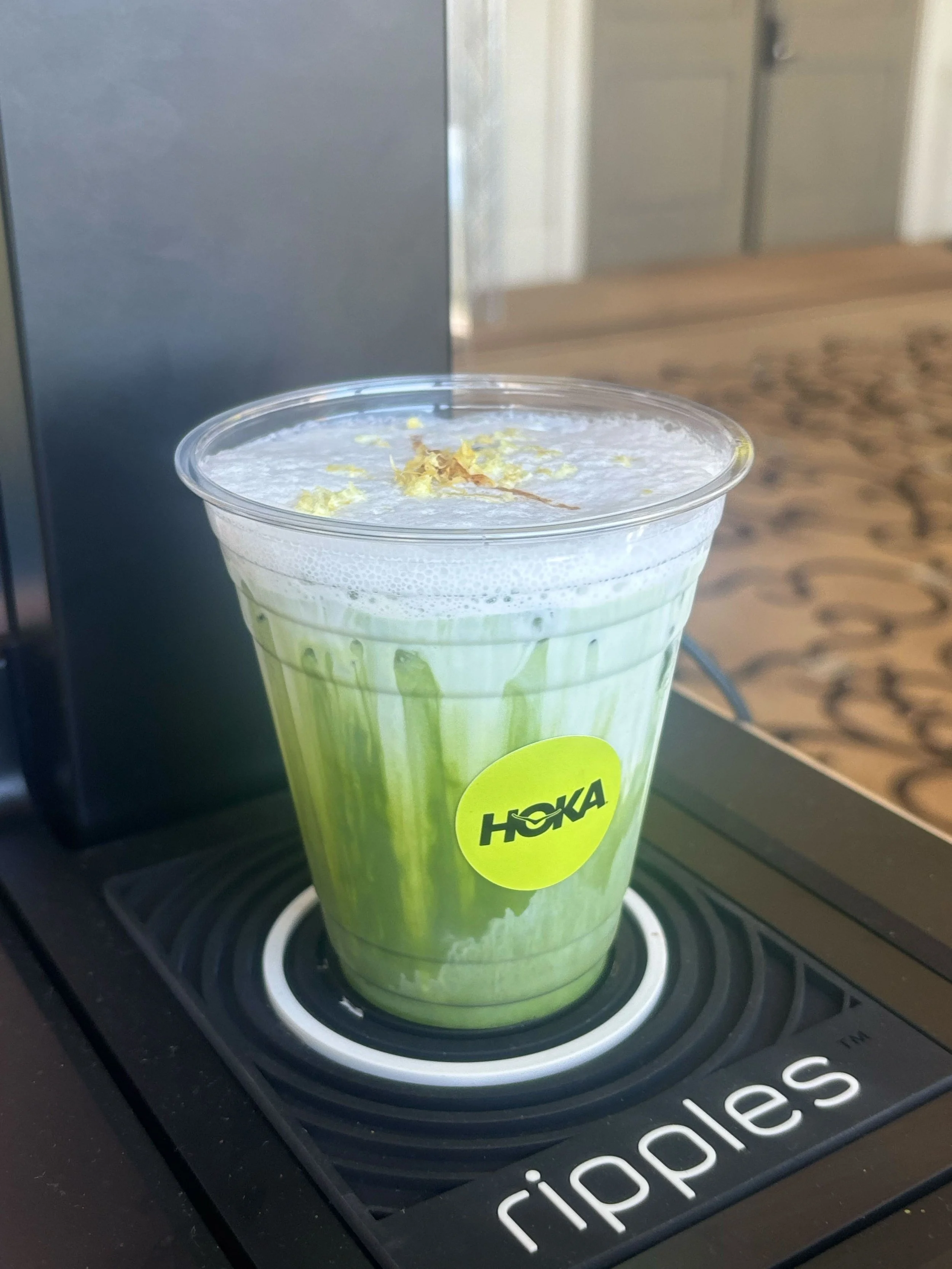 Pulo Coffee branded matcha latte with gold flake garnish and custom HOKA logo sticker at Los Angeles brand activation