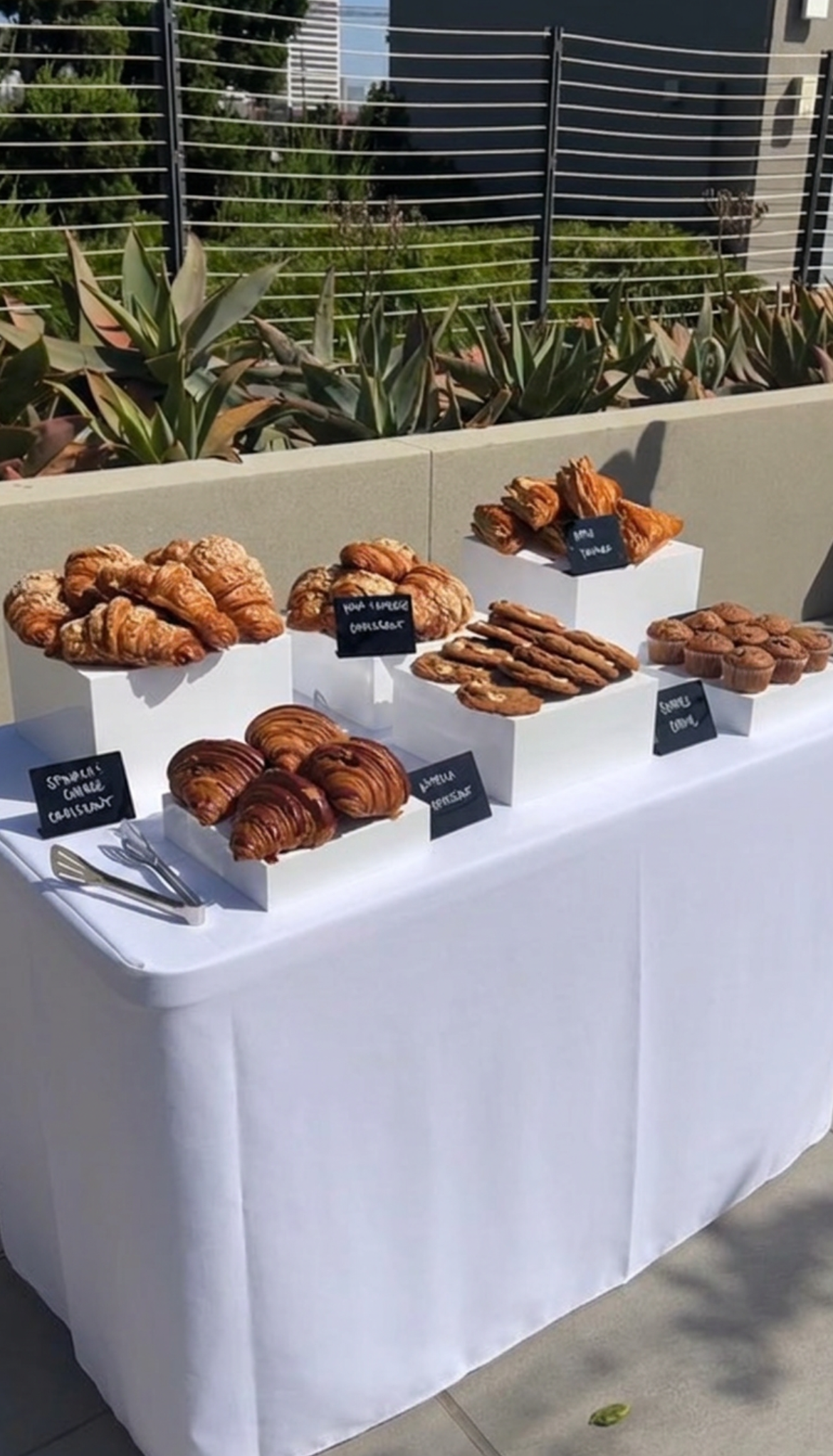 Assorted pastry table with risers and chalkboard labels at Pulo Coffee setup for Stanley x Kacey Musgraves collection launch in Los Angeles