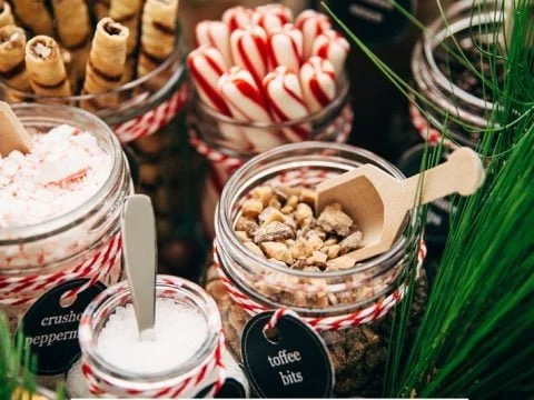 Premium hot chocolate cart toppings bar with candy canes, crushed peppermint, and toffee bits at a Pulo Coffee catering event in Los Angeles