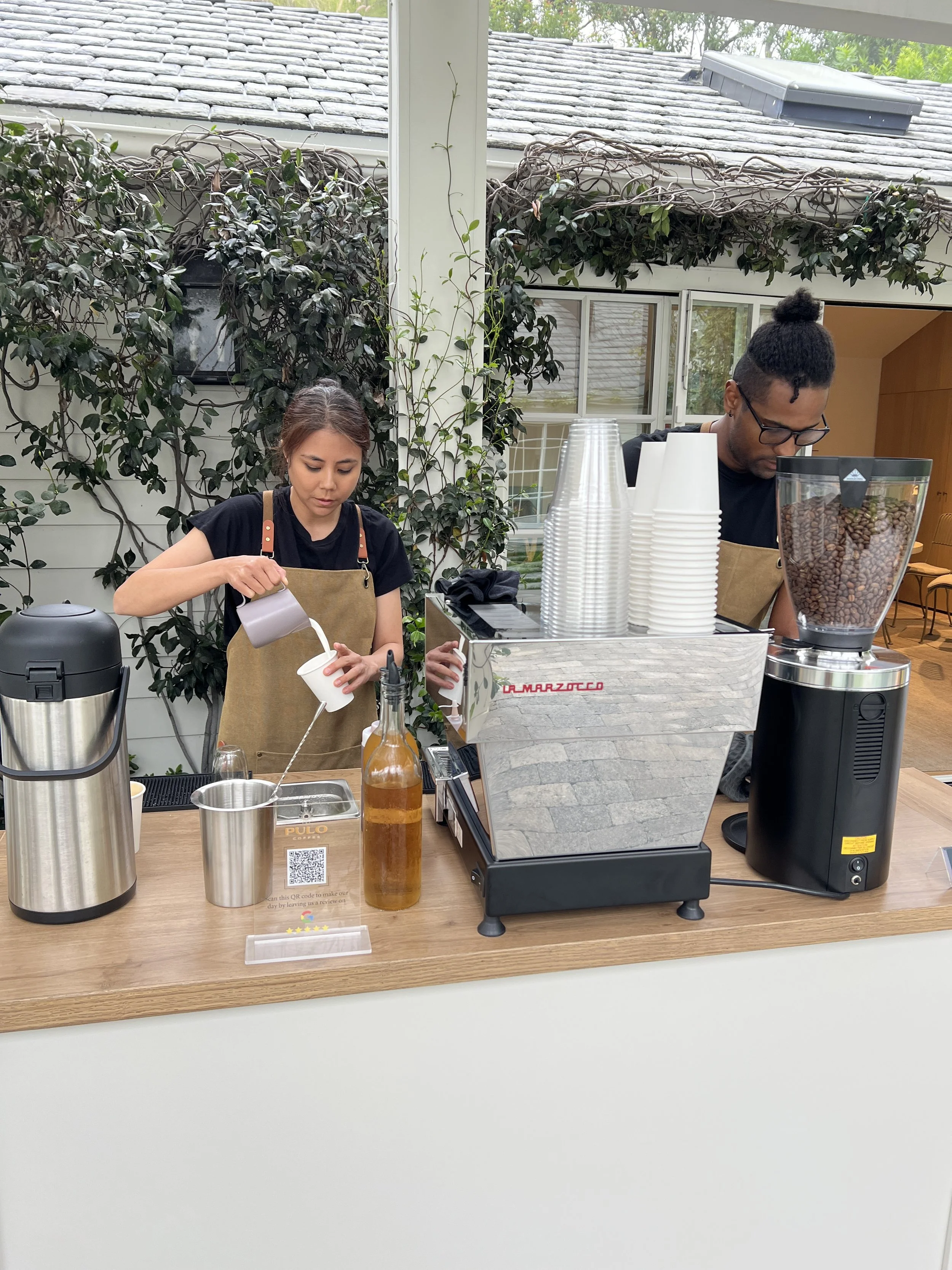 Two baristas creating latte art at a mobile espresso bar coffee cart