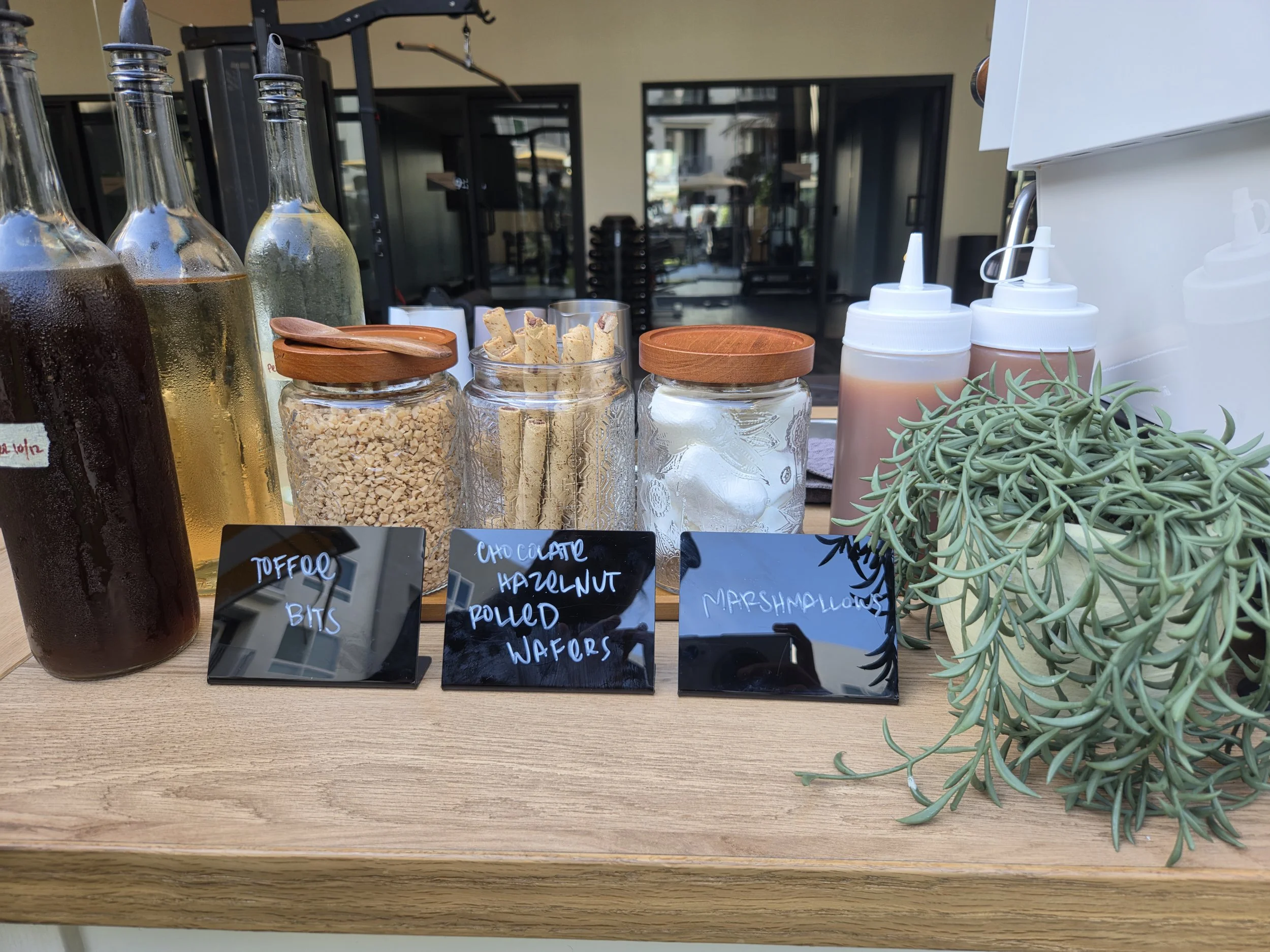 Hot chocolate bar toppings with toffee bits, chocolate hazelnut rolled wafers, marshmallows, and homemade syrups at a Pulo Coffee event in Los Angeles