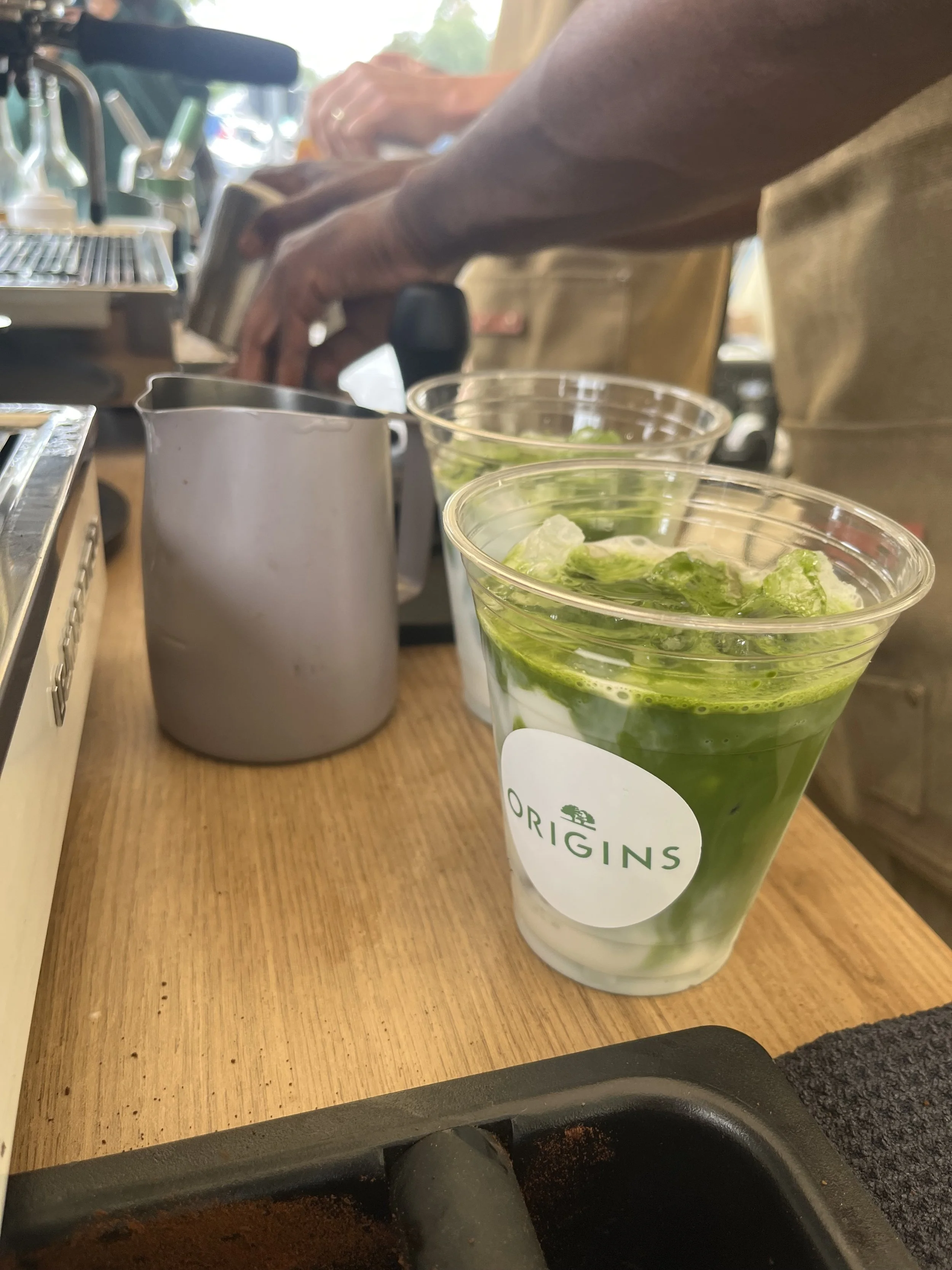 Iced matcha latte with Origins branded cup served by Pulo Coffee mobile matcha bar at a brand activation in Los Angeles