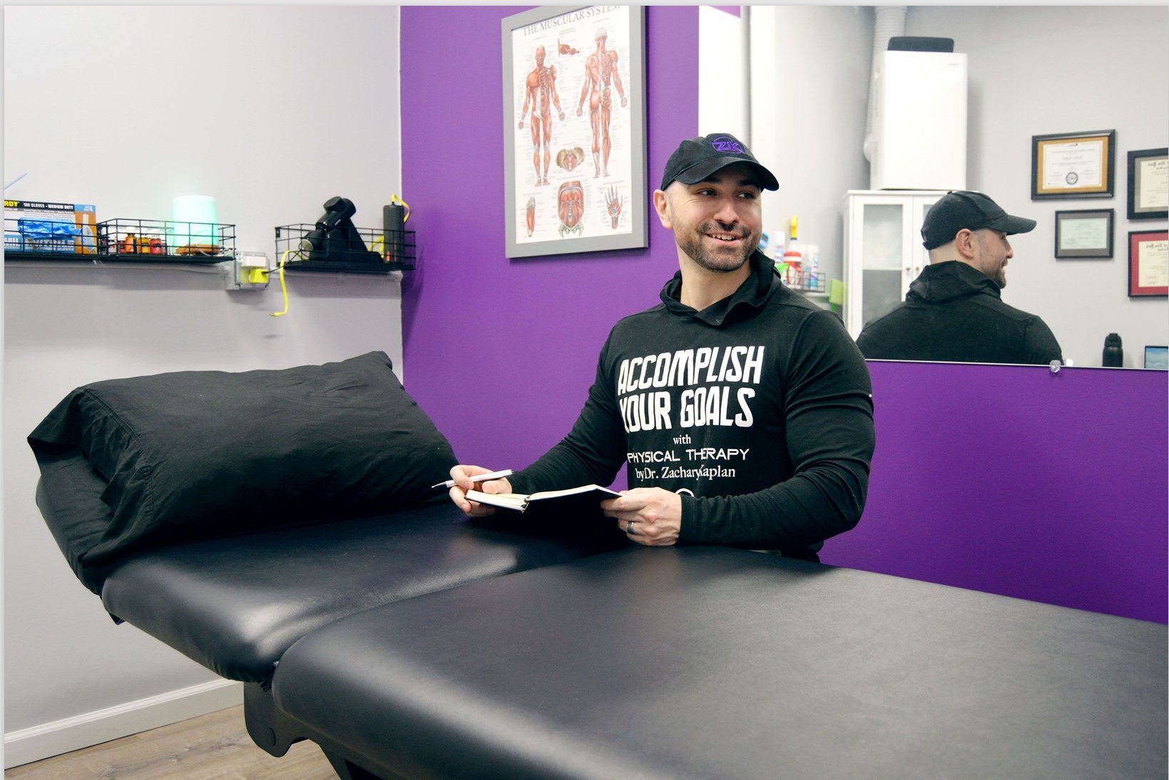 Dr. Zack Kaplan sitting near his clinic bench with a notebook in his office