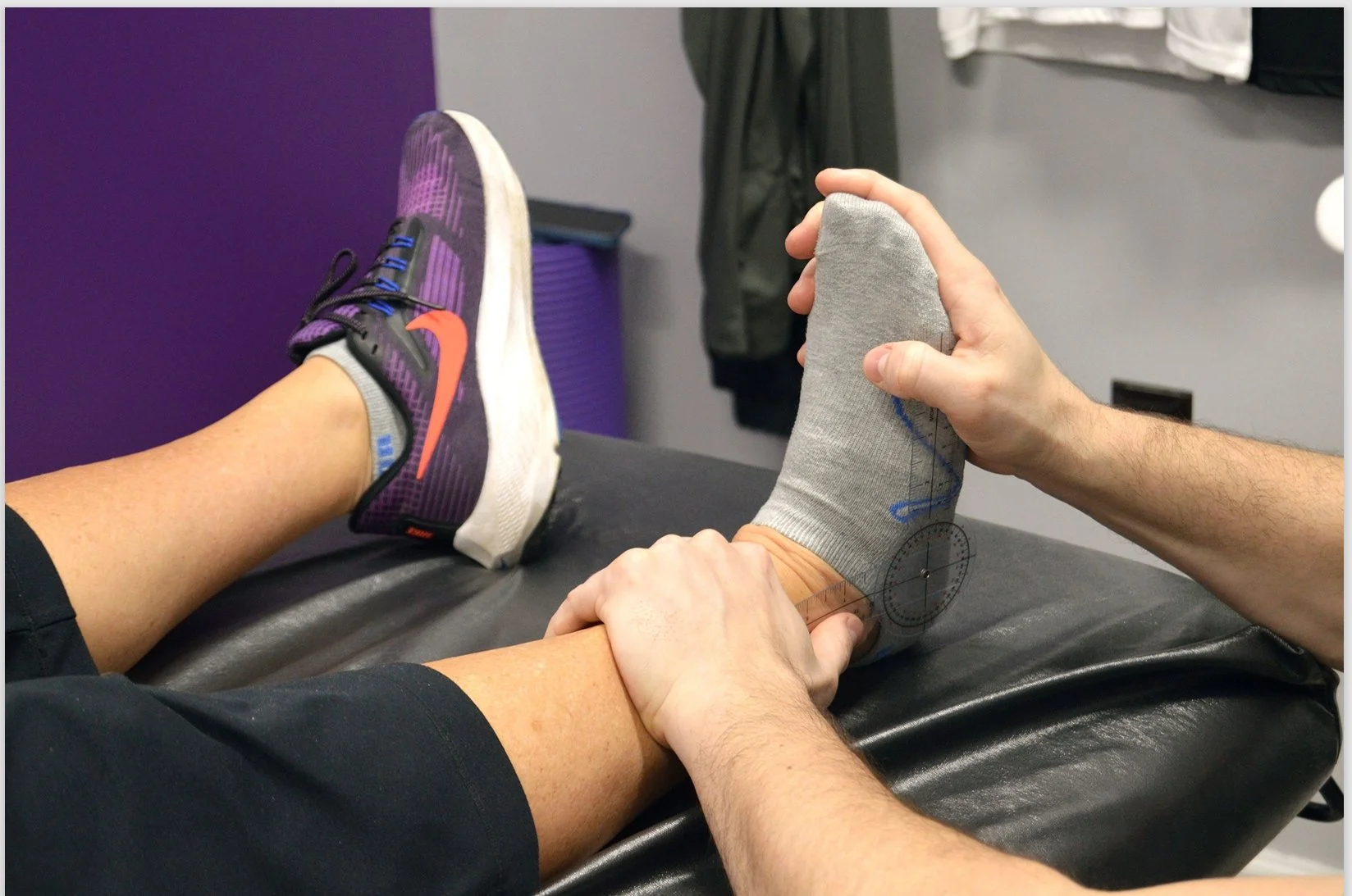 Dr. Zach Kaplan is measuring a patient's foot on a bench in the office