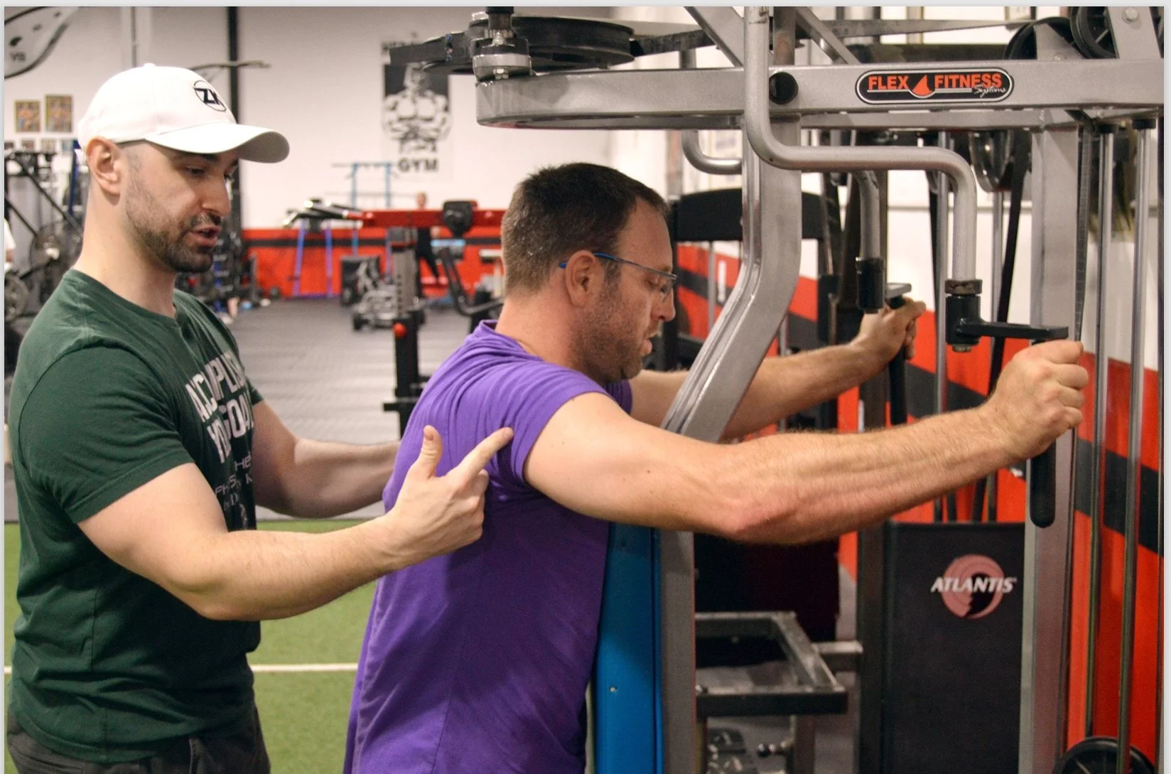 Dr. Zach Kaplan helping patient on physical therapy machine to target shoulder area
