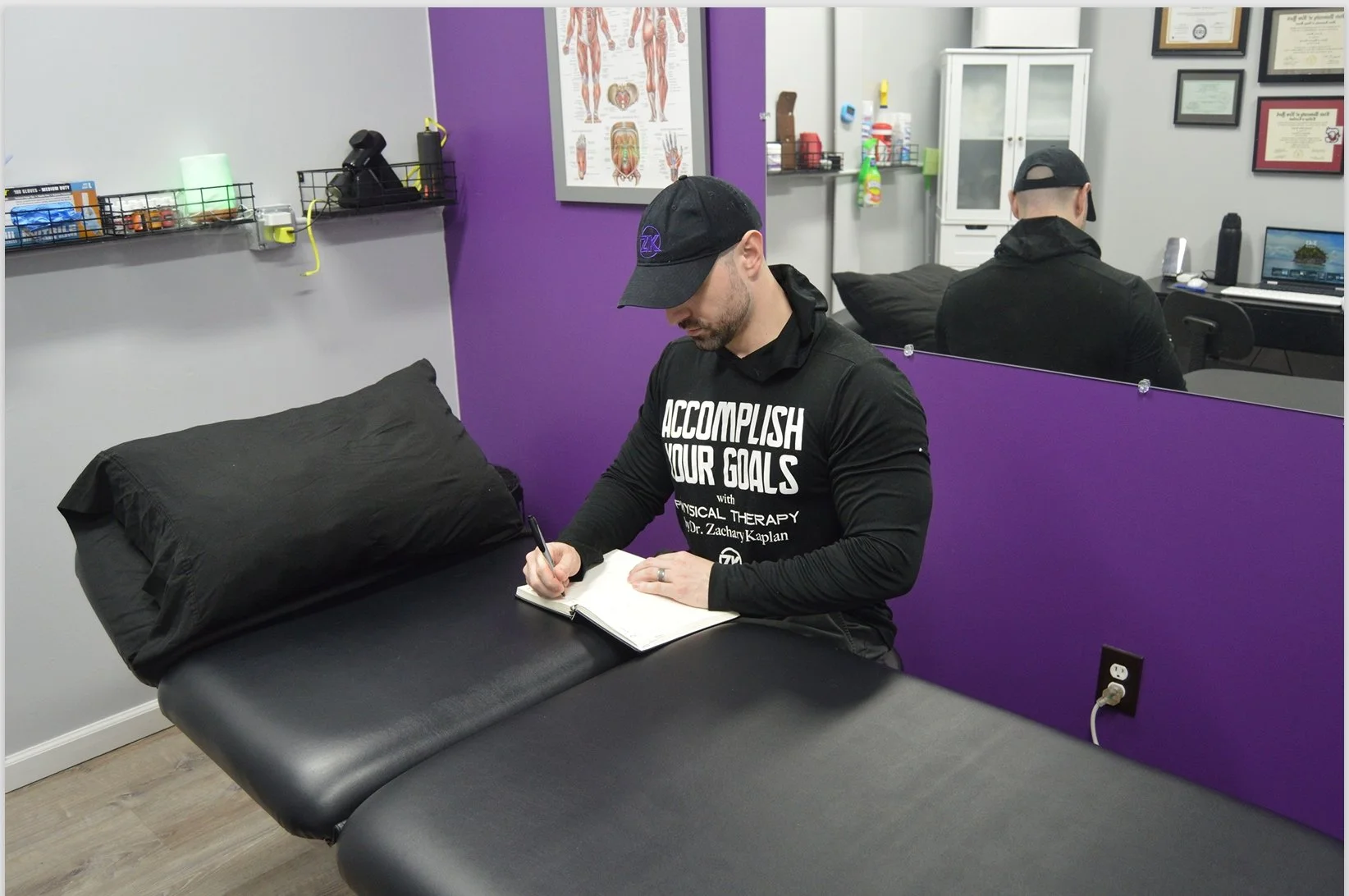 Dr. Zach Kaplan sitting by his clinic bench writing in a notebook at the office