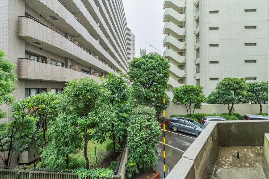 都市のマンションの駐車場と緑の木々