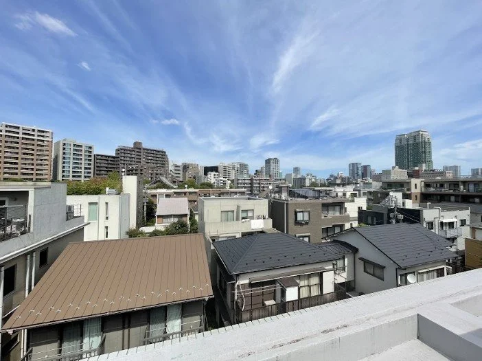 都心の高層ビルと住宅街の景色、青空と雲が広がる都市の風景