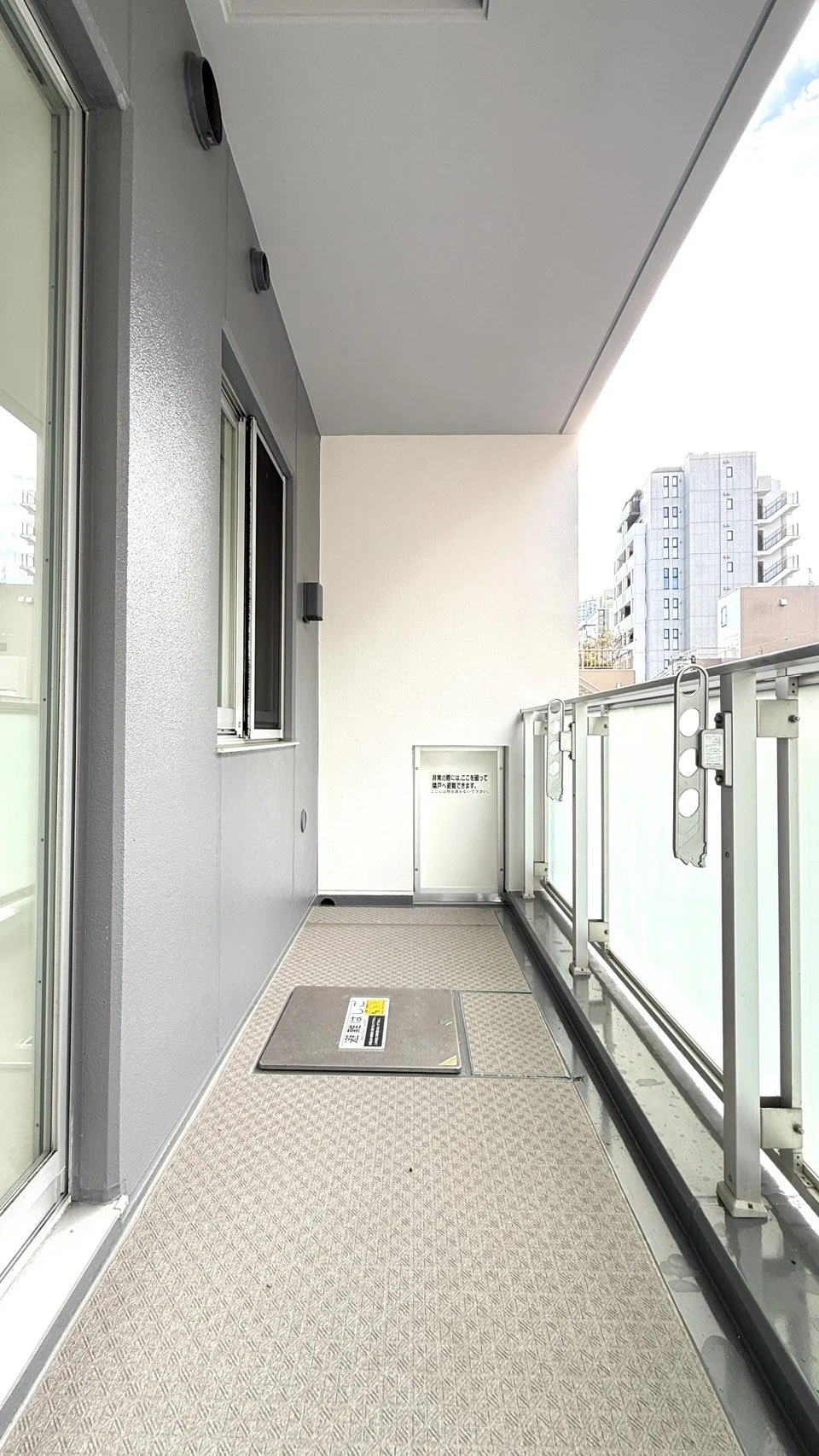 建物のバルコニー、金属製の手すりと長方形の階段扉が見える