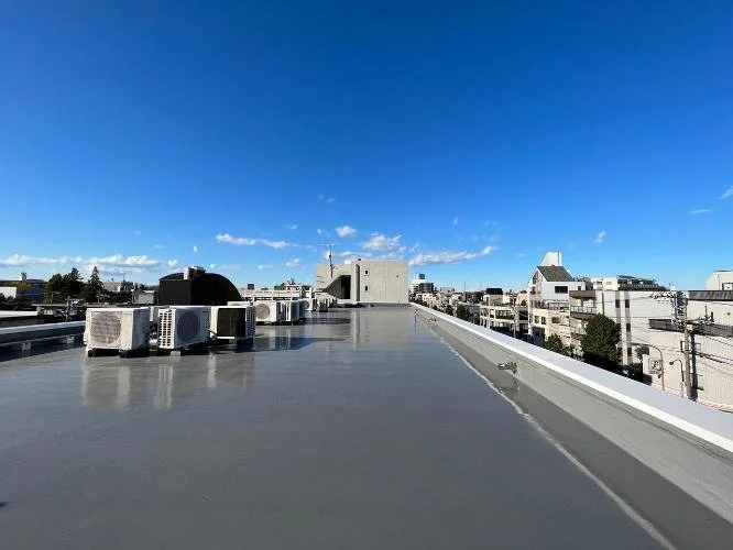 都市のビルの屋上から見た青空と白い建物群