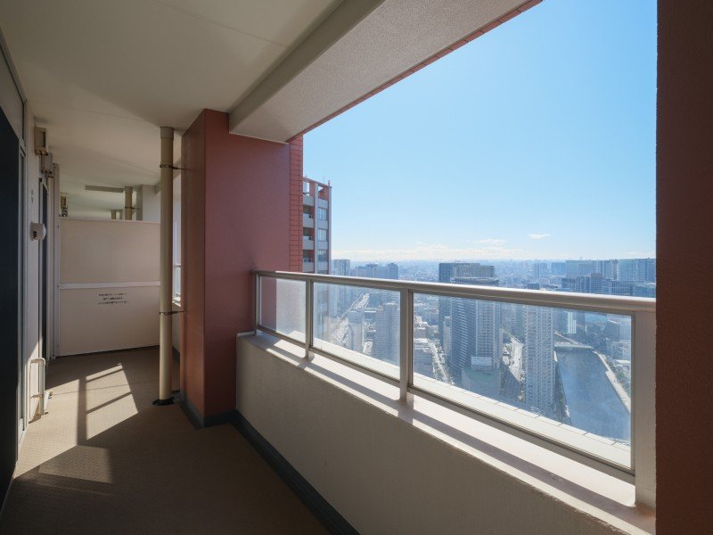 高層ビルのバルコニーからの都市の眺め、青空と多くのビルが見える