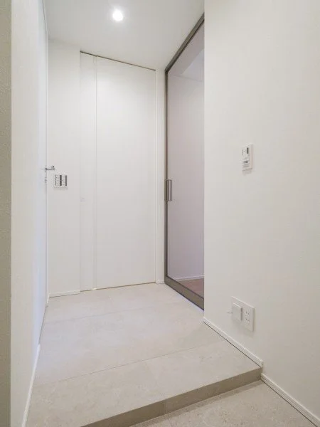 白い壁とドア、ガラス扉のある室内のエントランス部分