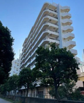 高層の白いマンションと周囲の樹木、青空