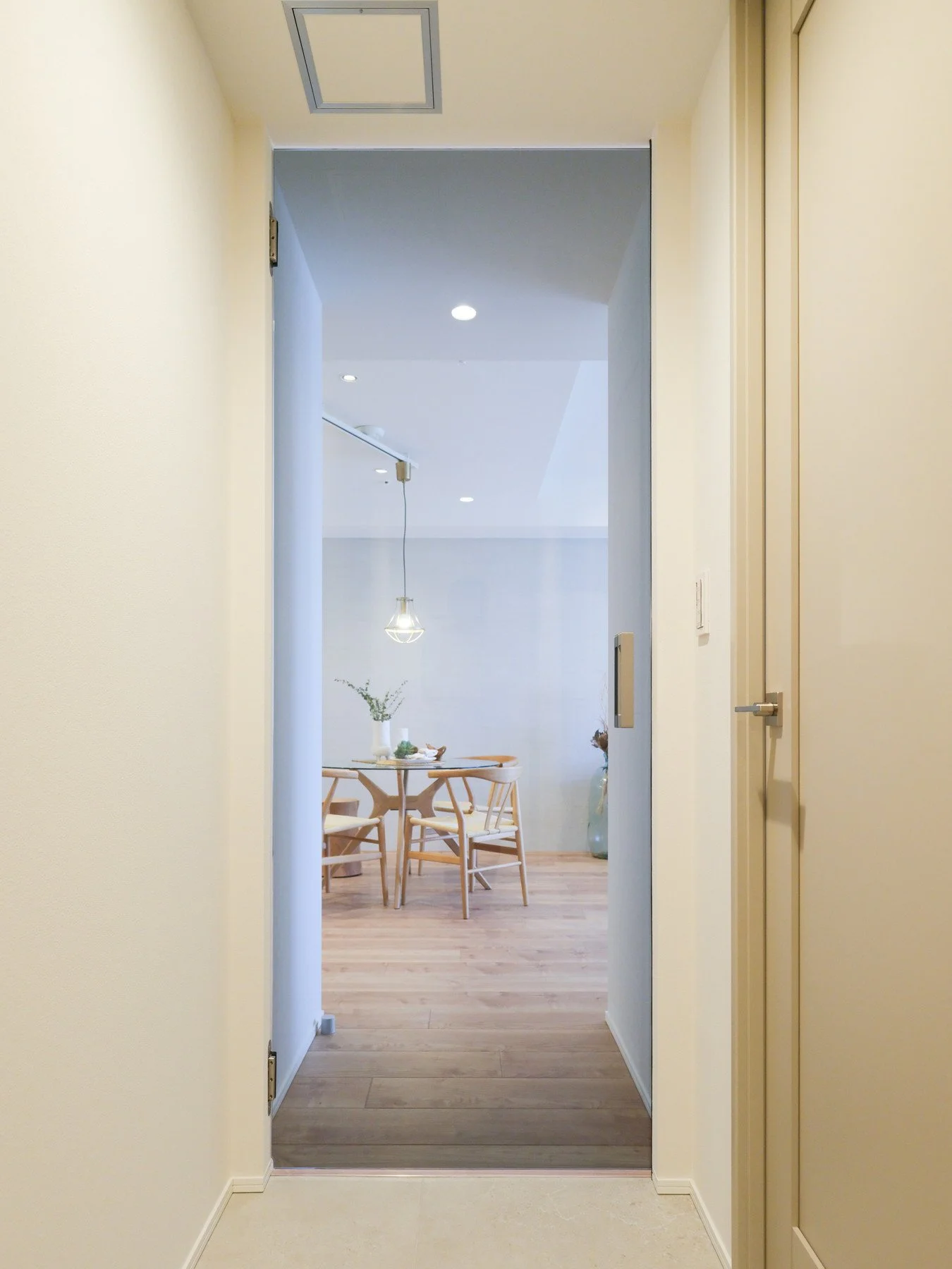 リビングルームの入り口から見た、木製のダイニングテーブルと椅子、花瓶と飾りのある室内