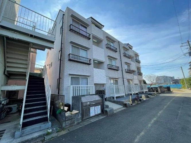 白い四階建てのアパートの外観と駐車場