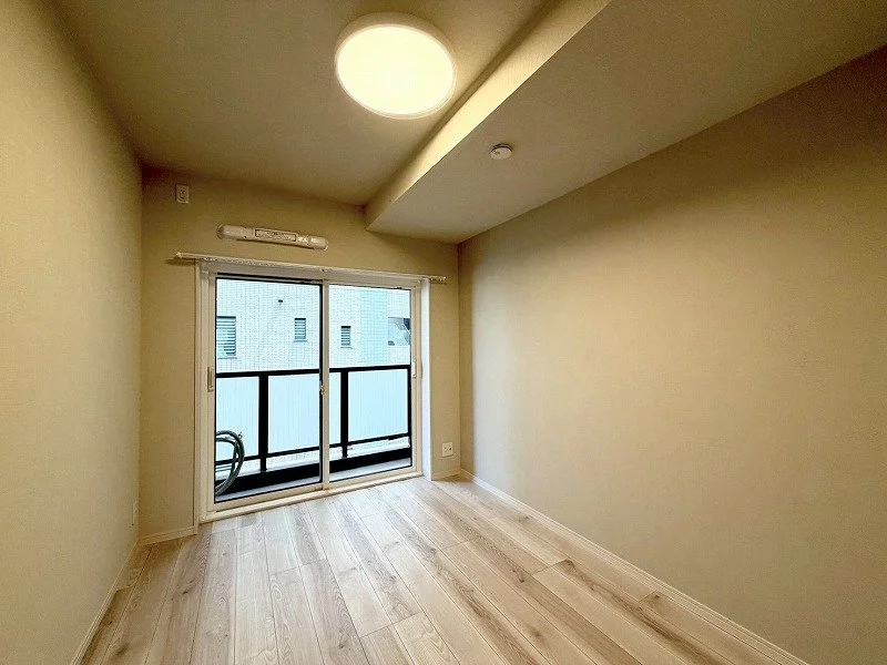 空っぽの部屋、窓とバルコニー、木製の床、暖色の壁照明と天井照明