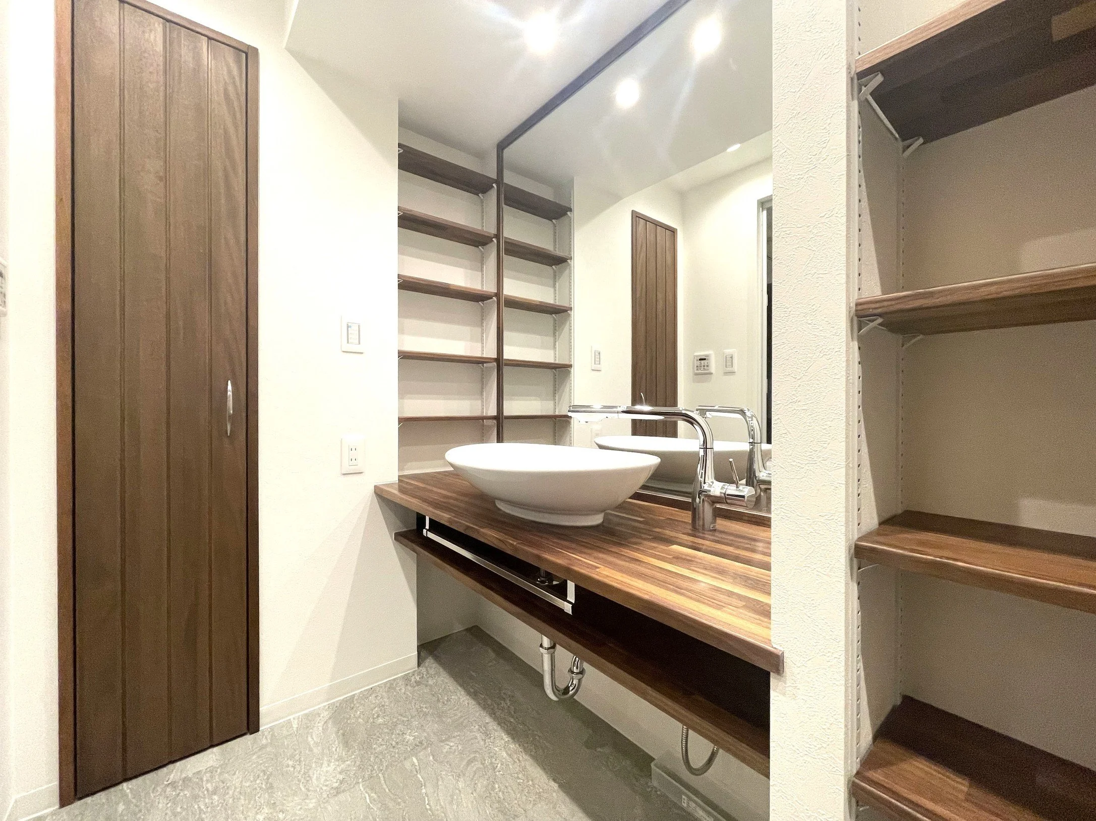 木製の棚と洗面台のあるモダンな洗面所の interior。