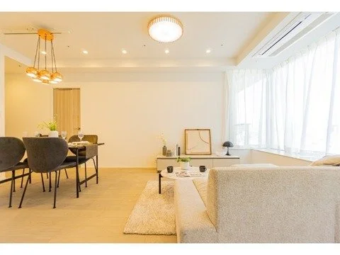 明るくシンプルなリビングルームとダイニングエリア、ソファとダイニングテーブルが置かれている。