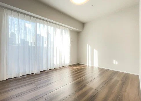 白い壁と木製の床の空の部屋、窓から自然光が入っている