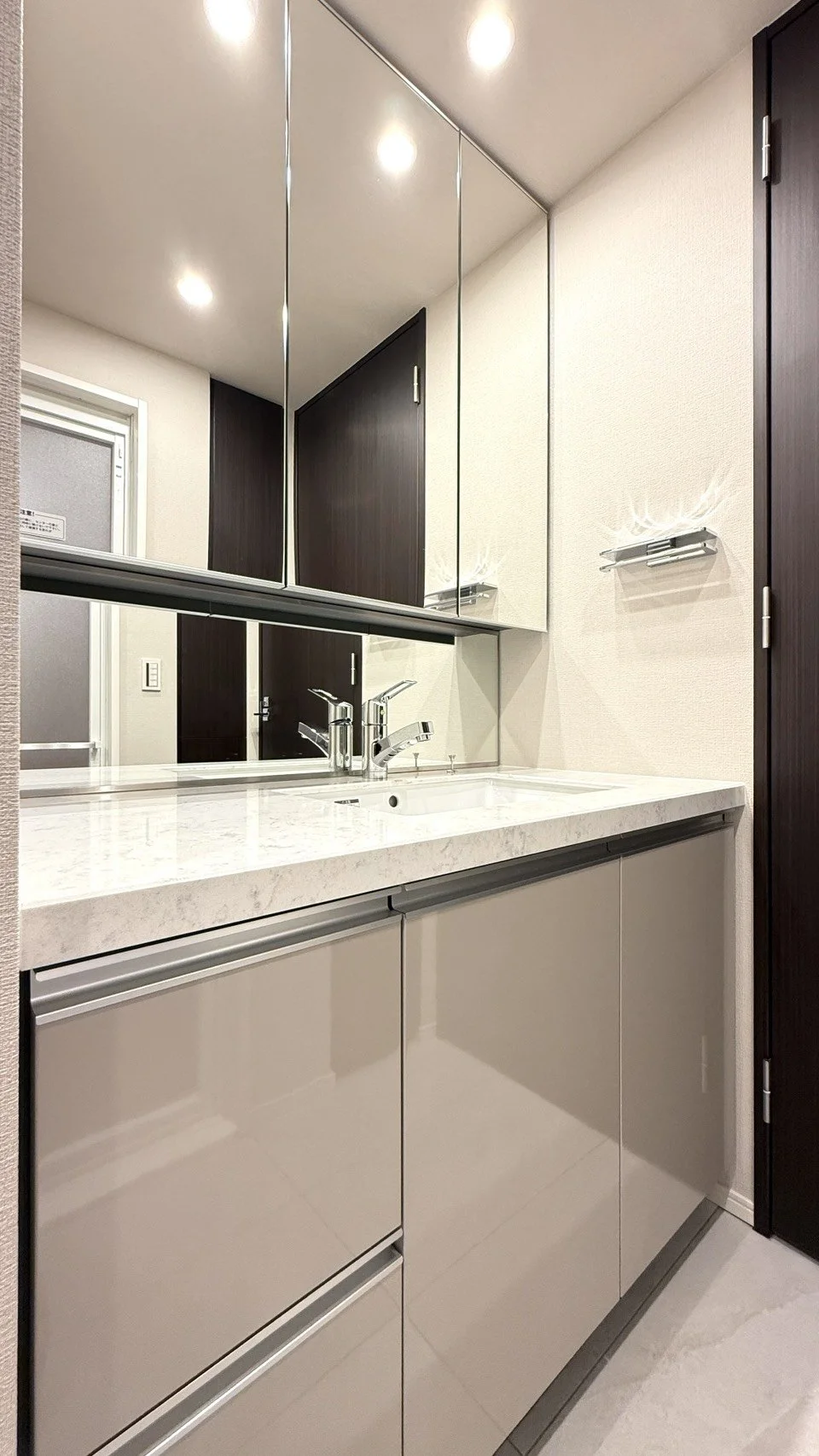 洗面台と鏡、洗面所の収納棚があるモダンな洗面エリアの写真