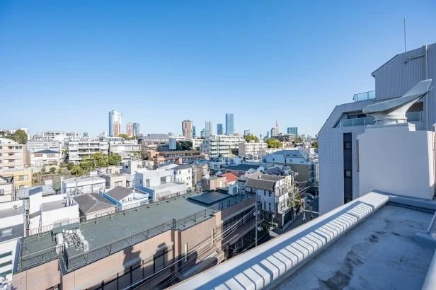 都市のビル群と青空の眺め。手すりのある屋上からの景色。