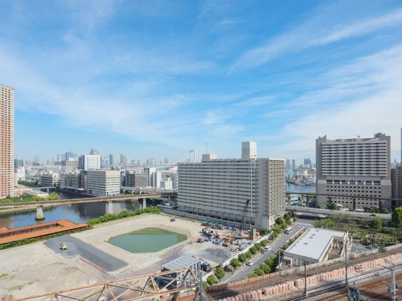 都市の景色、川と高層ビル、青空と一部の建設工事現場
