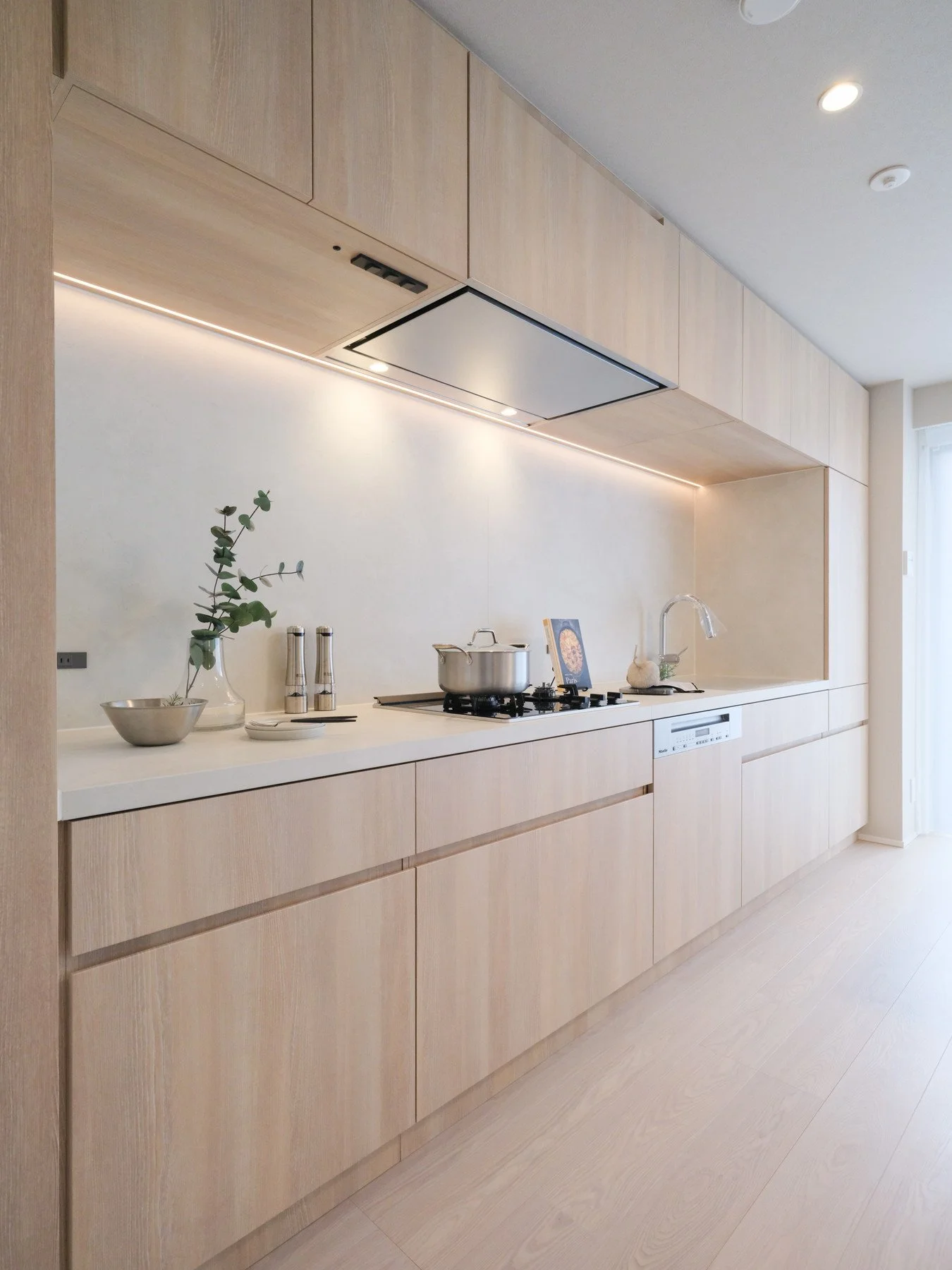 木目調のキッチンのカウンターとキャビネット、シンプルなデザインで明るい空間