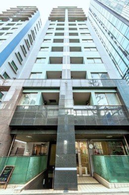 高層ビルの正面からの眺め。建物の中央に柱があり、両側にガラス窓と balconies。