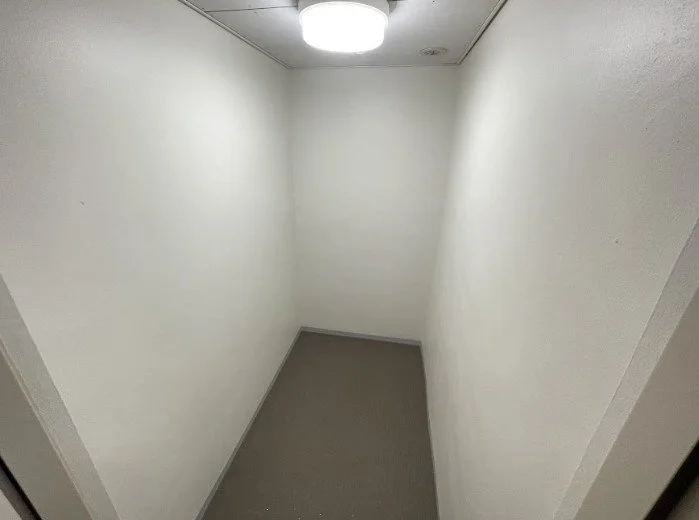 白い壁と床の小さな部屋、天井に照明がついている