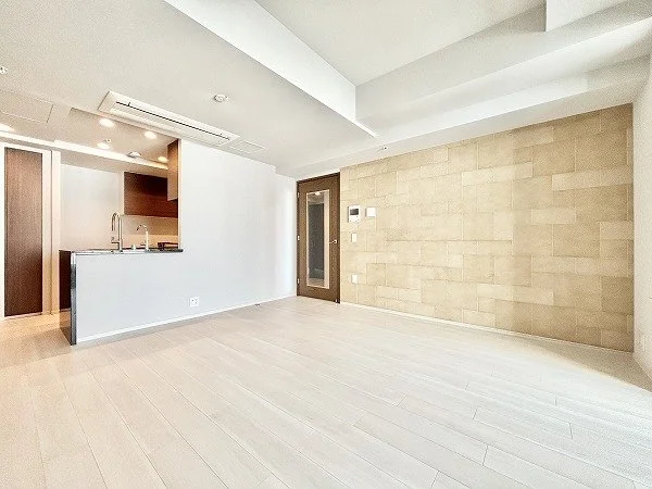 空のリビングルームとキッチンエリア、木製の床と白い壁、暖色系の壁紙とドア