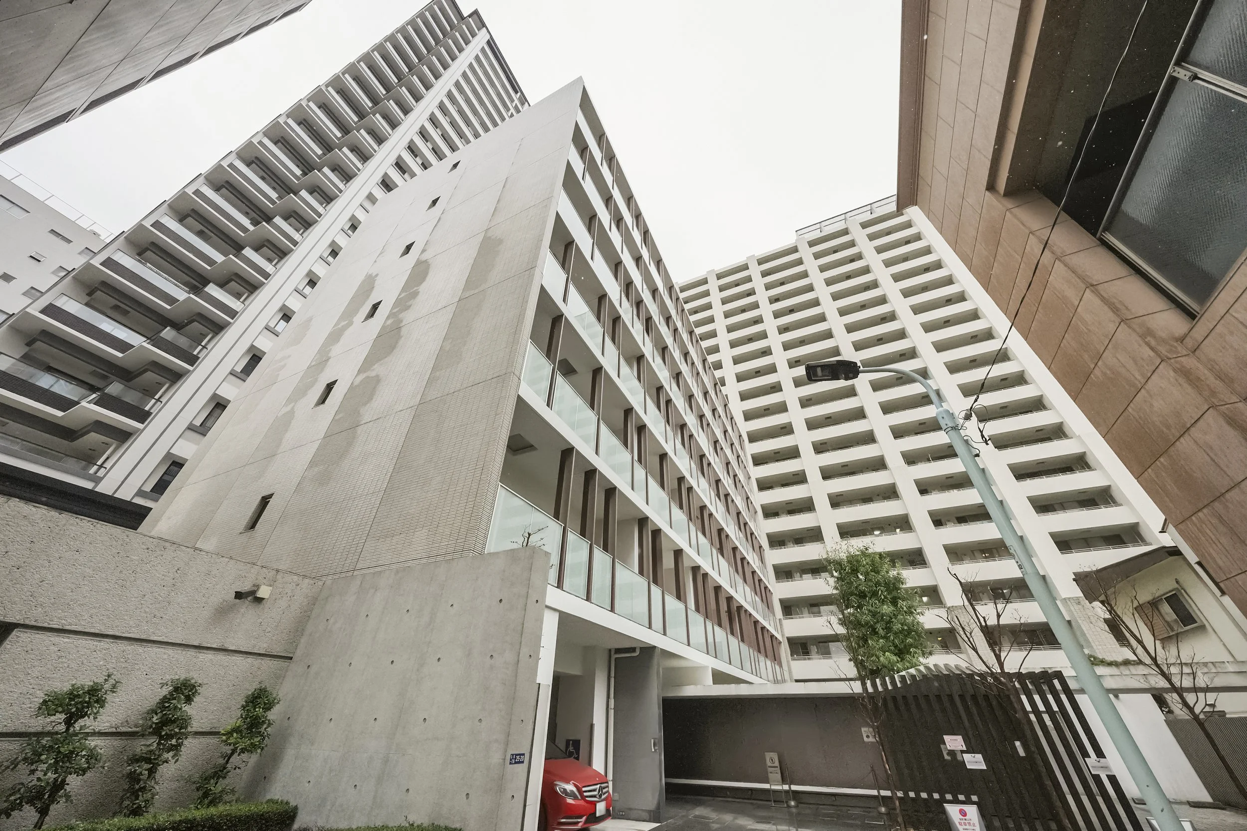 高層マンションの建物と街灯、車、木々が写っている都市の風景