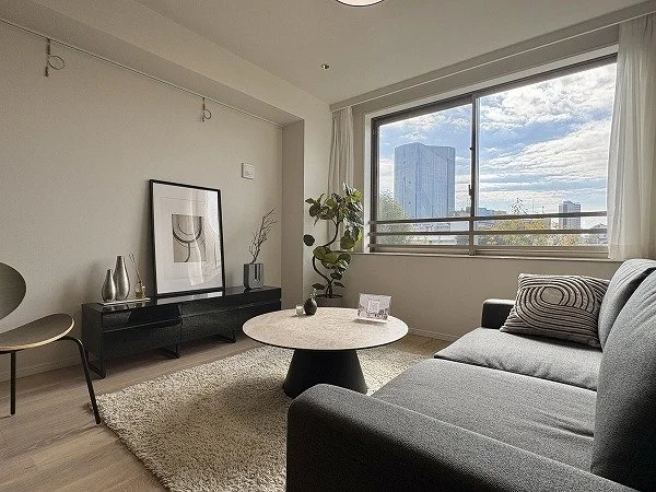 リビングルームのインテリア、ソファ、丸いテーブルと観葉植物、大きな窓から都市の景色が見える